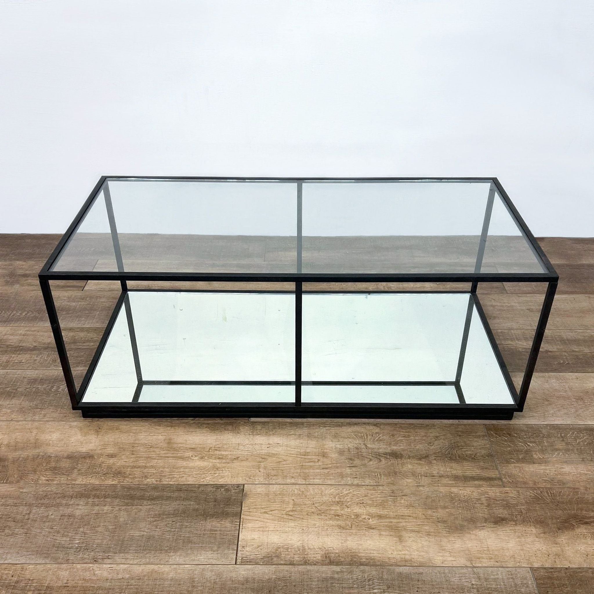 Reperch brand coffee table with a sleek metal box frame and clear glass top on a wooden floor.