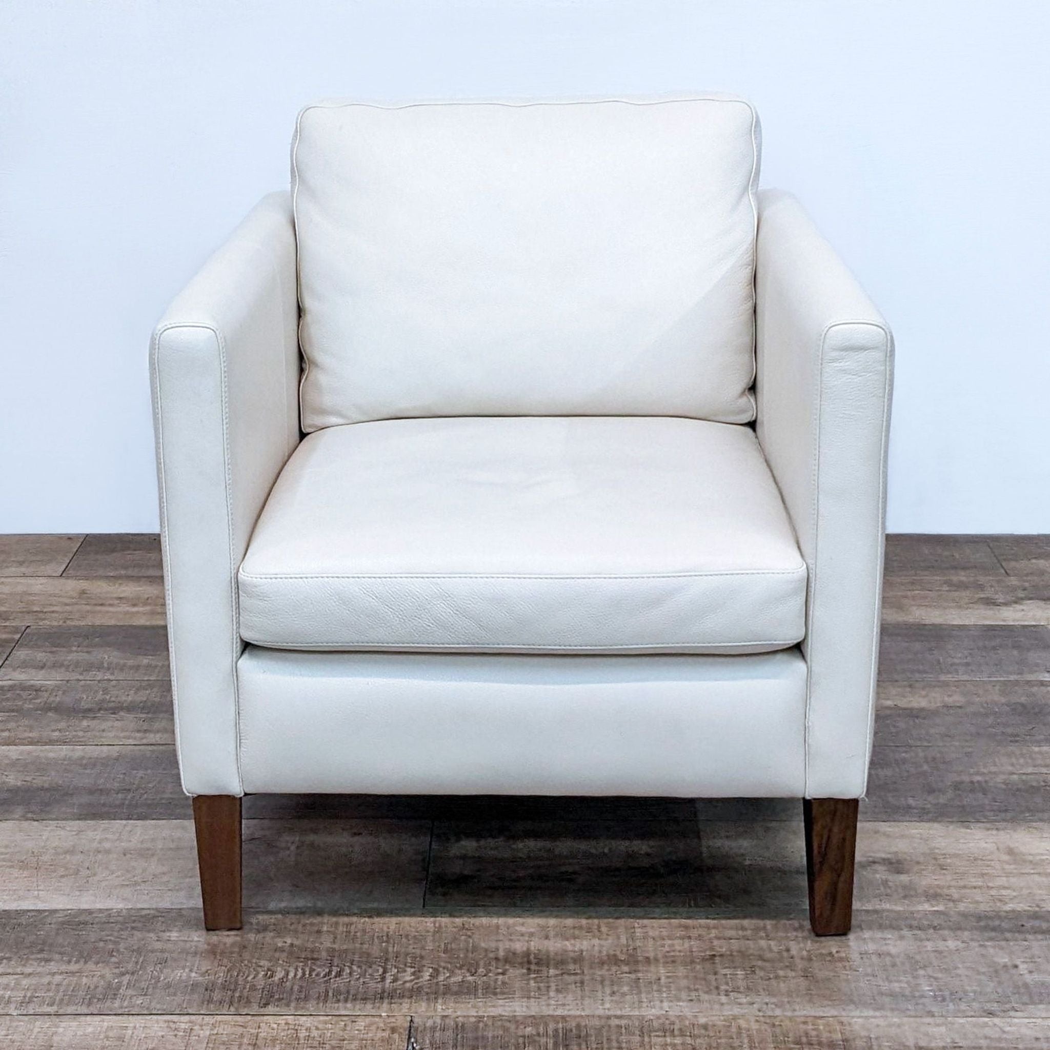Front view of a white leather Kent chair by Room & Board with walnut wood feet.