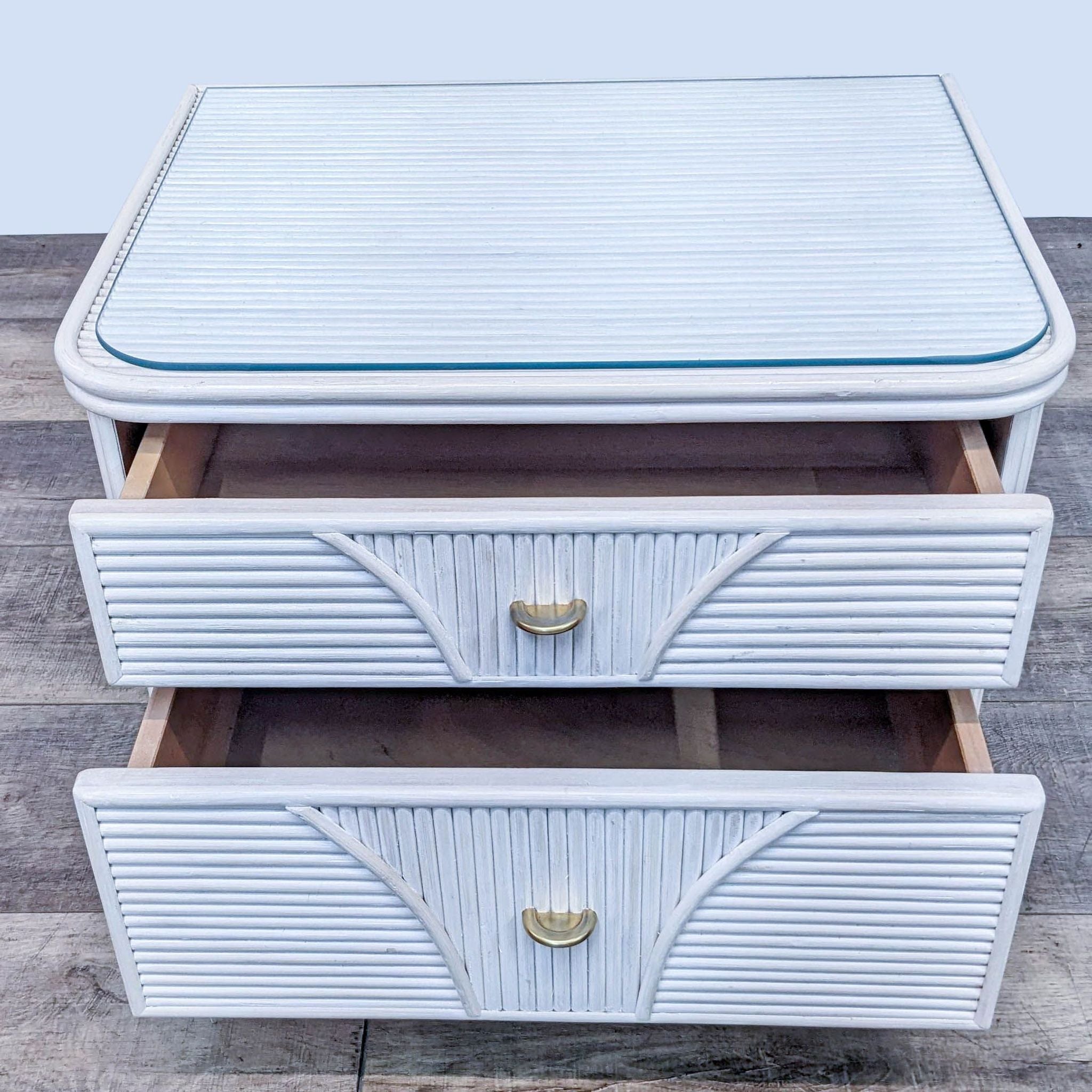 Front view of an open drawer on a textured Reperch end table with a glass top, against a wooden floor backdrop.