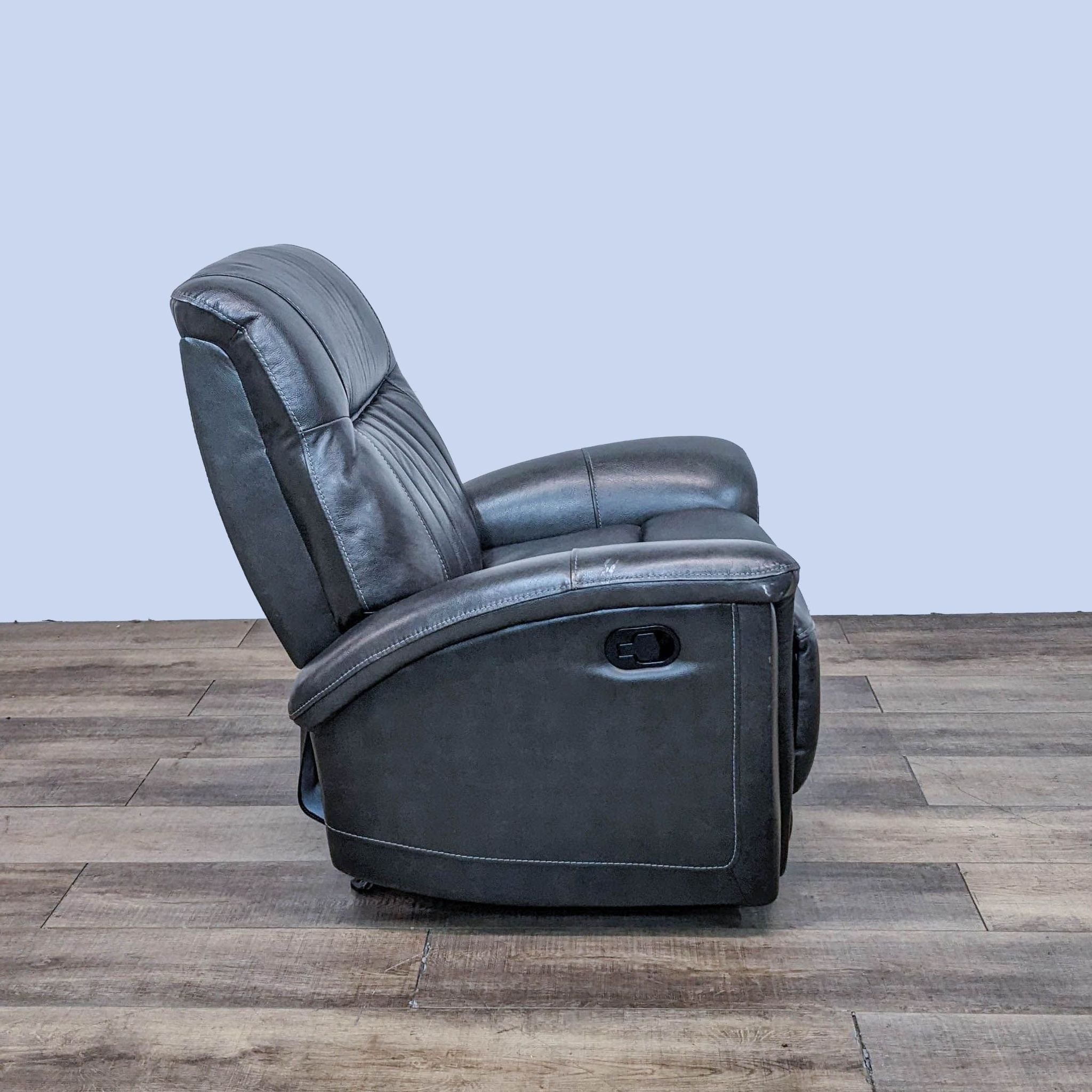 Rear view of Home Meridian leather recliner showing vertical stitching and compact design, hardwood floor background.