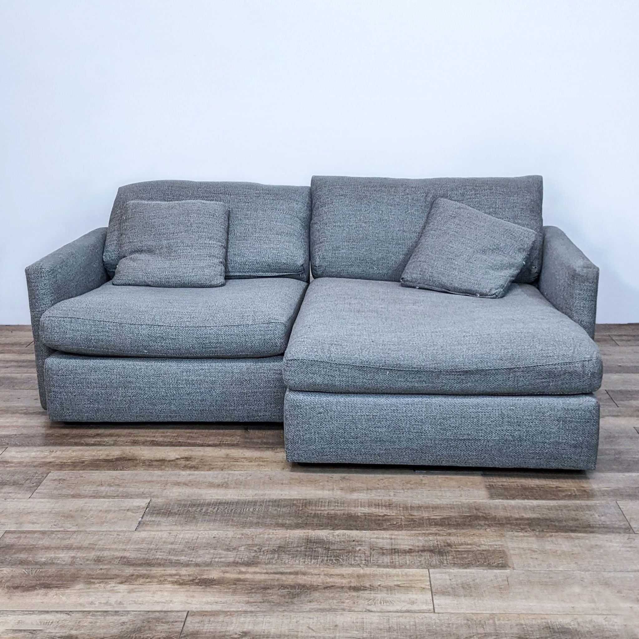 1. "Crate & Barrel modern two-piece sectional in a neutral gray fabric with narrow track arms and plush cushions, against a plain background."