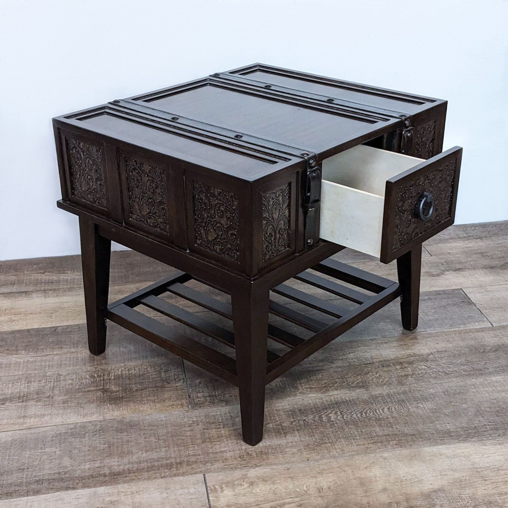 Open drawer on a Reperch end table showcasing ornate design and interior, with leather straps and slatted lower shelf.