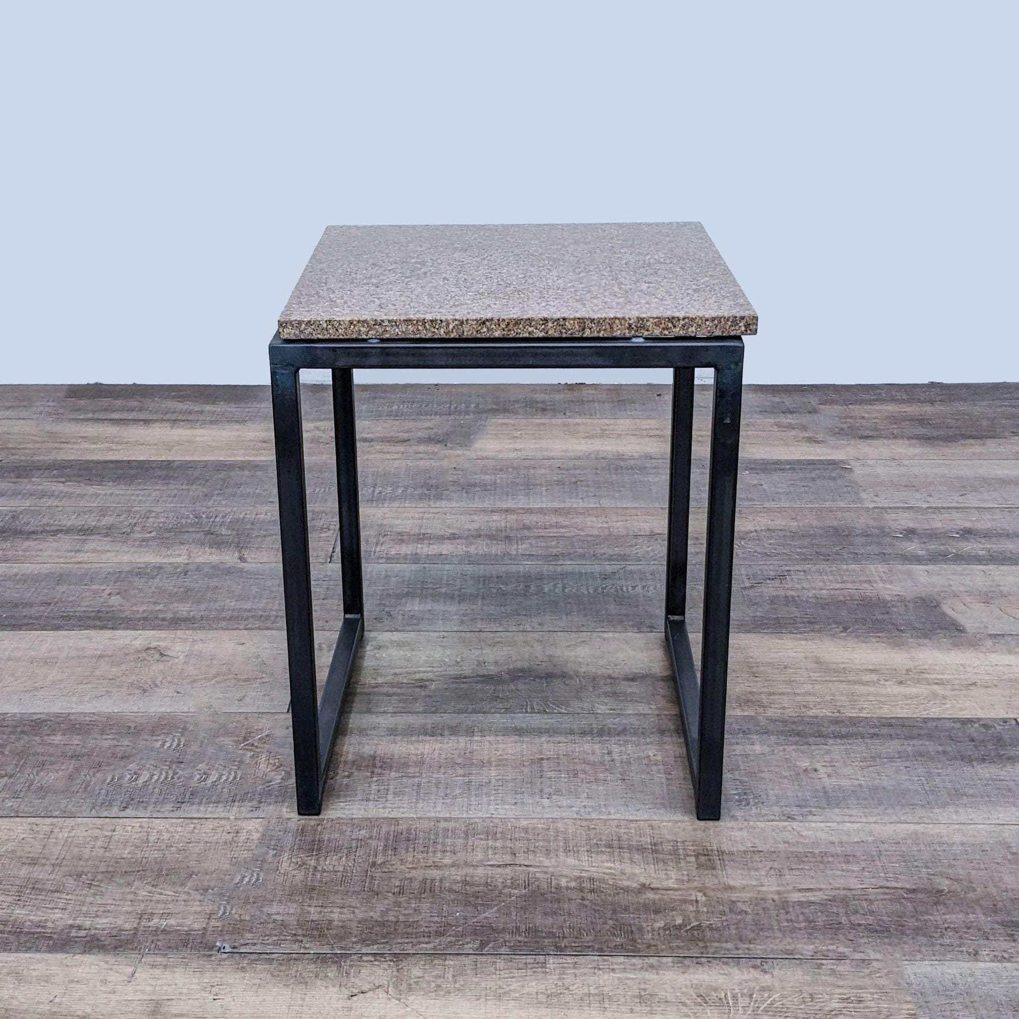 Room & Board side table with metal base and speckled top, shown in front view on a wooden floor.