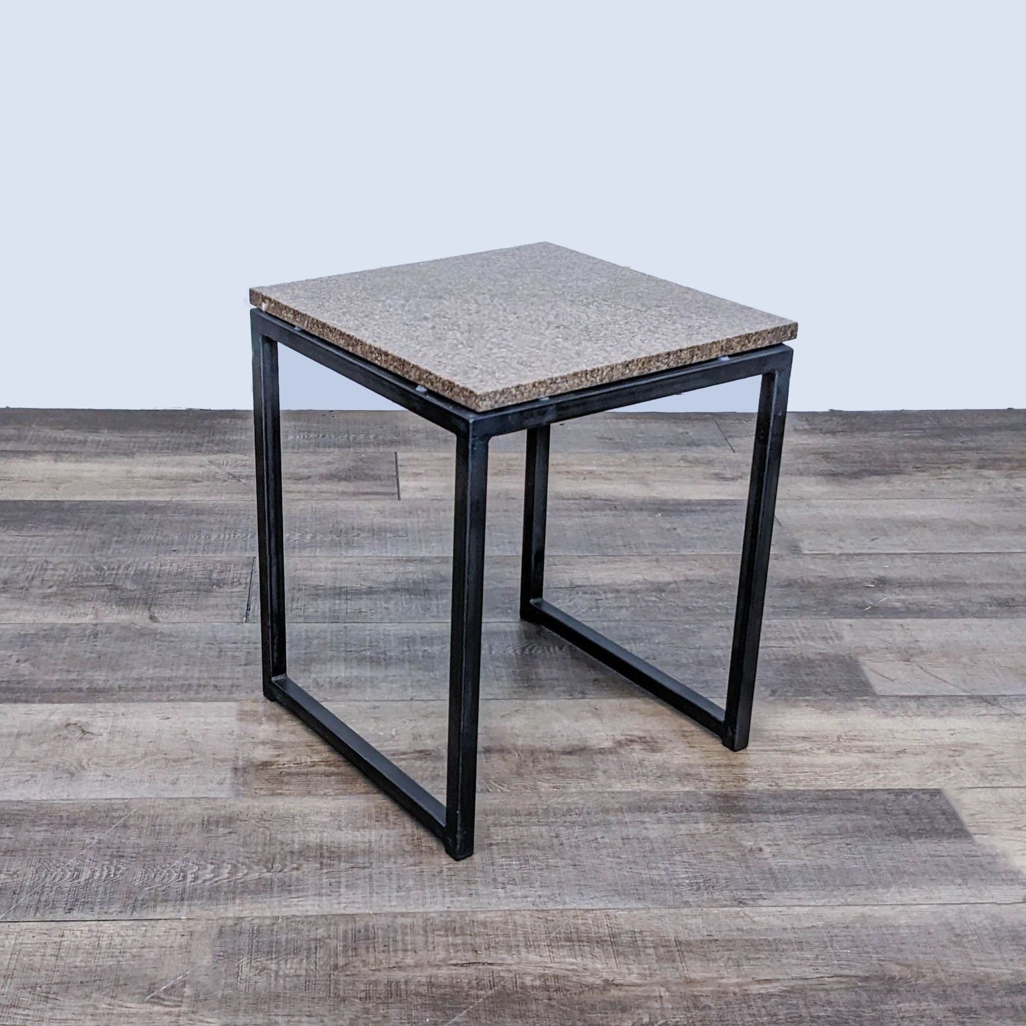 Angled view of Room & Board console table, featuring metal legs and textured top, on a hardwood floor.
