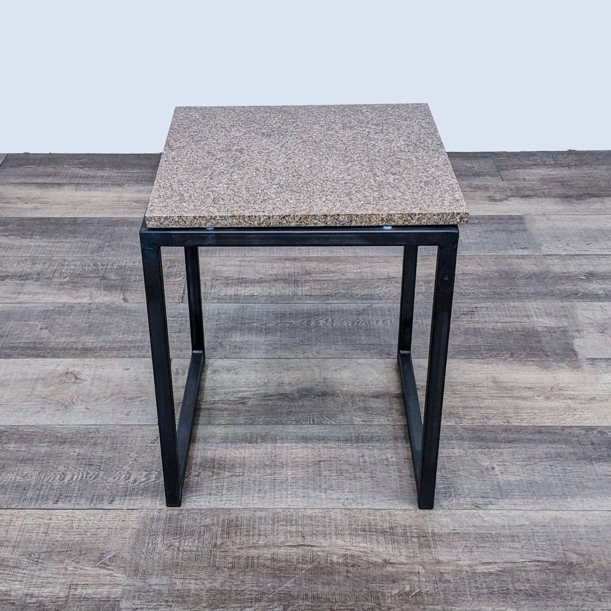 Room & Board side table with a speckled top and metal base on a wood floor.