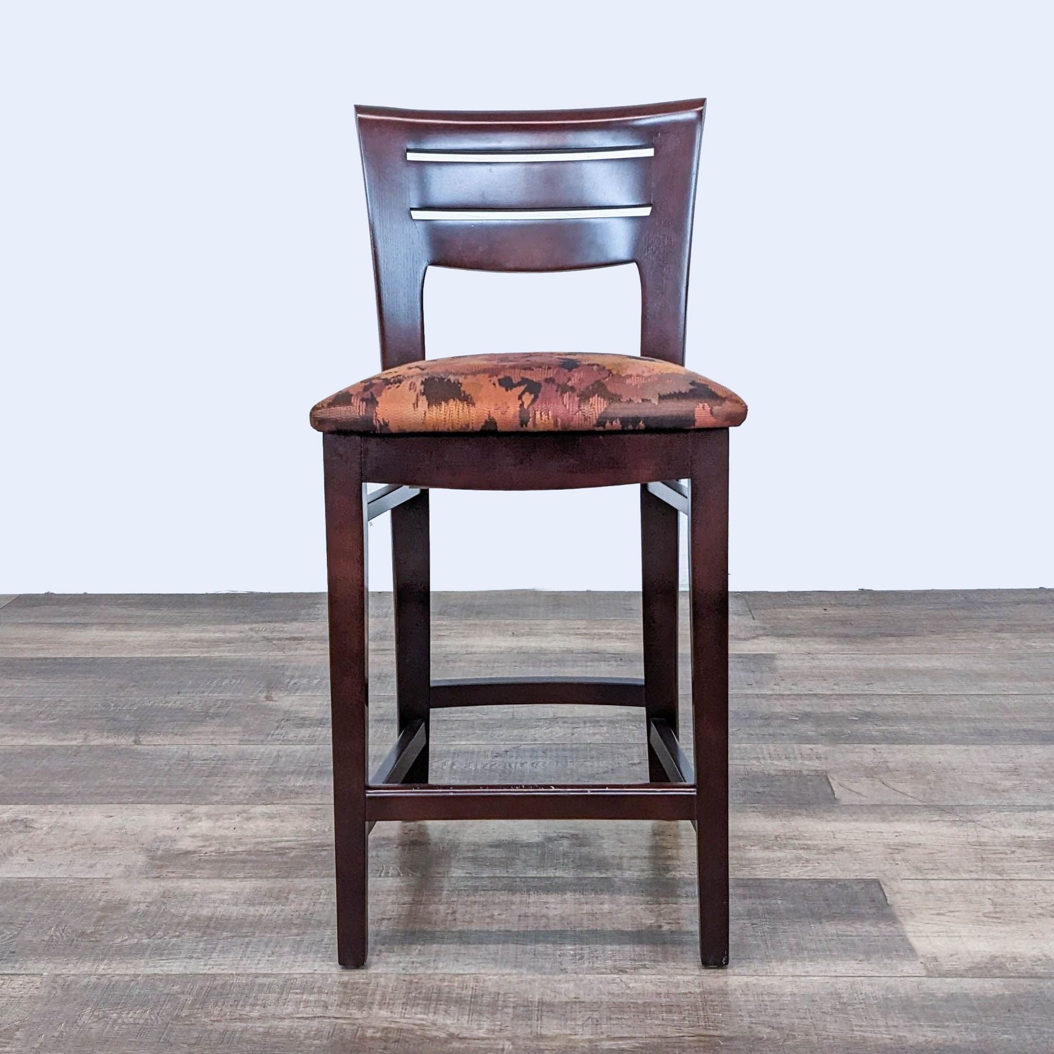 Reperch stool with a dark wood frame and seat covered in earth-toned fabric pattern.