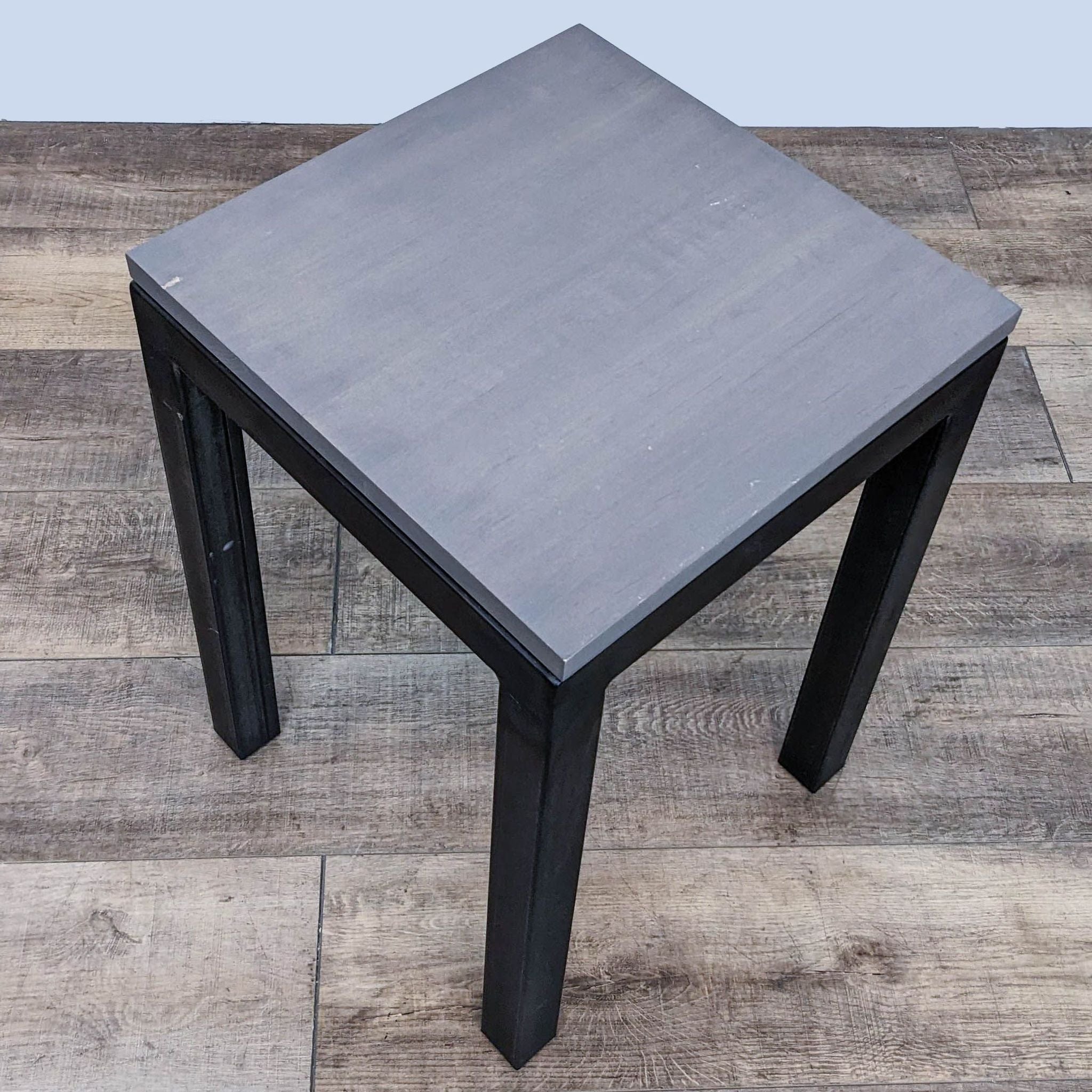 Room & Board side table with dark metal base on a wooden floor.