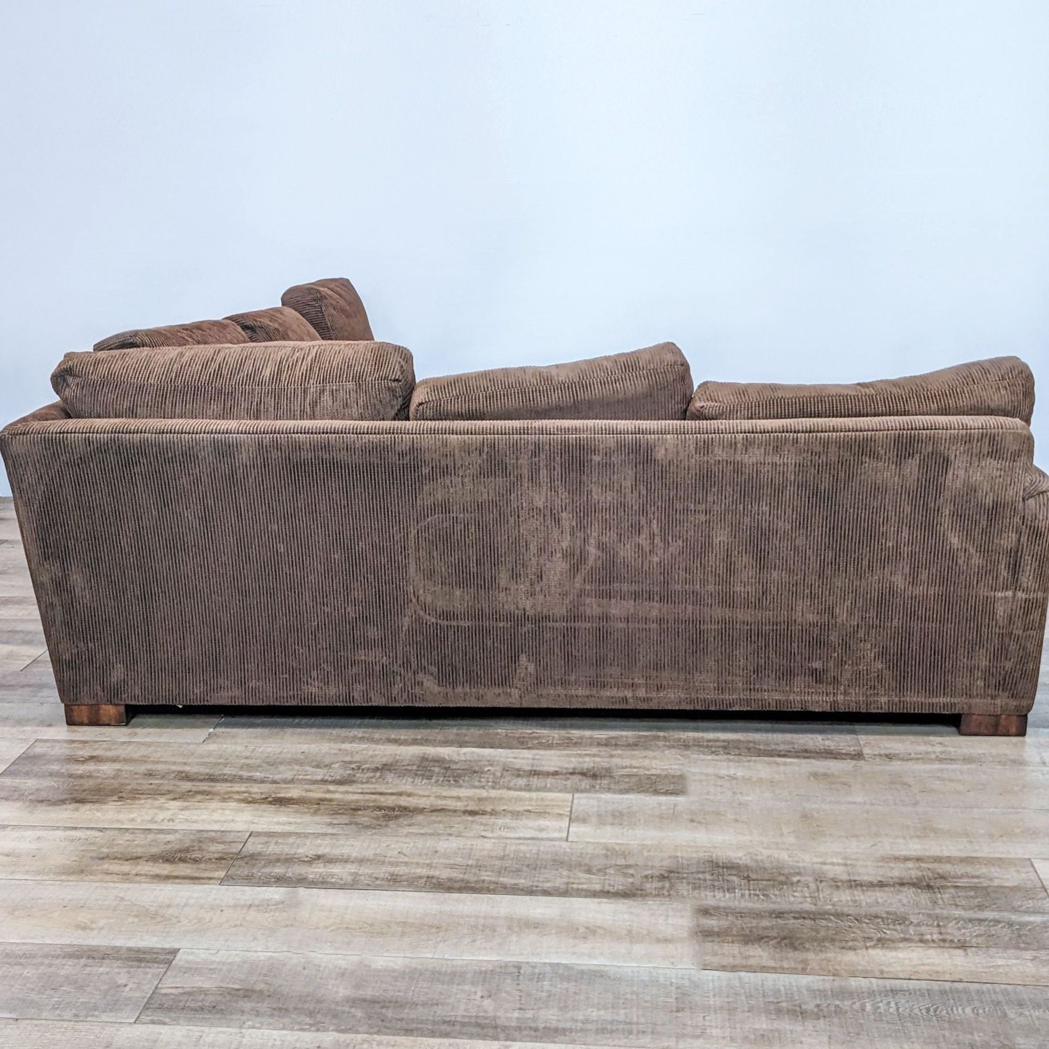 Brown Flexsteel two-piece sectional with plush cushions and wooden block feet on laminate flooring.