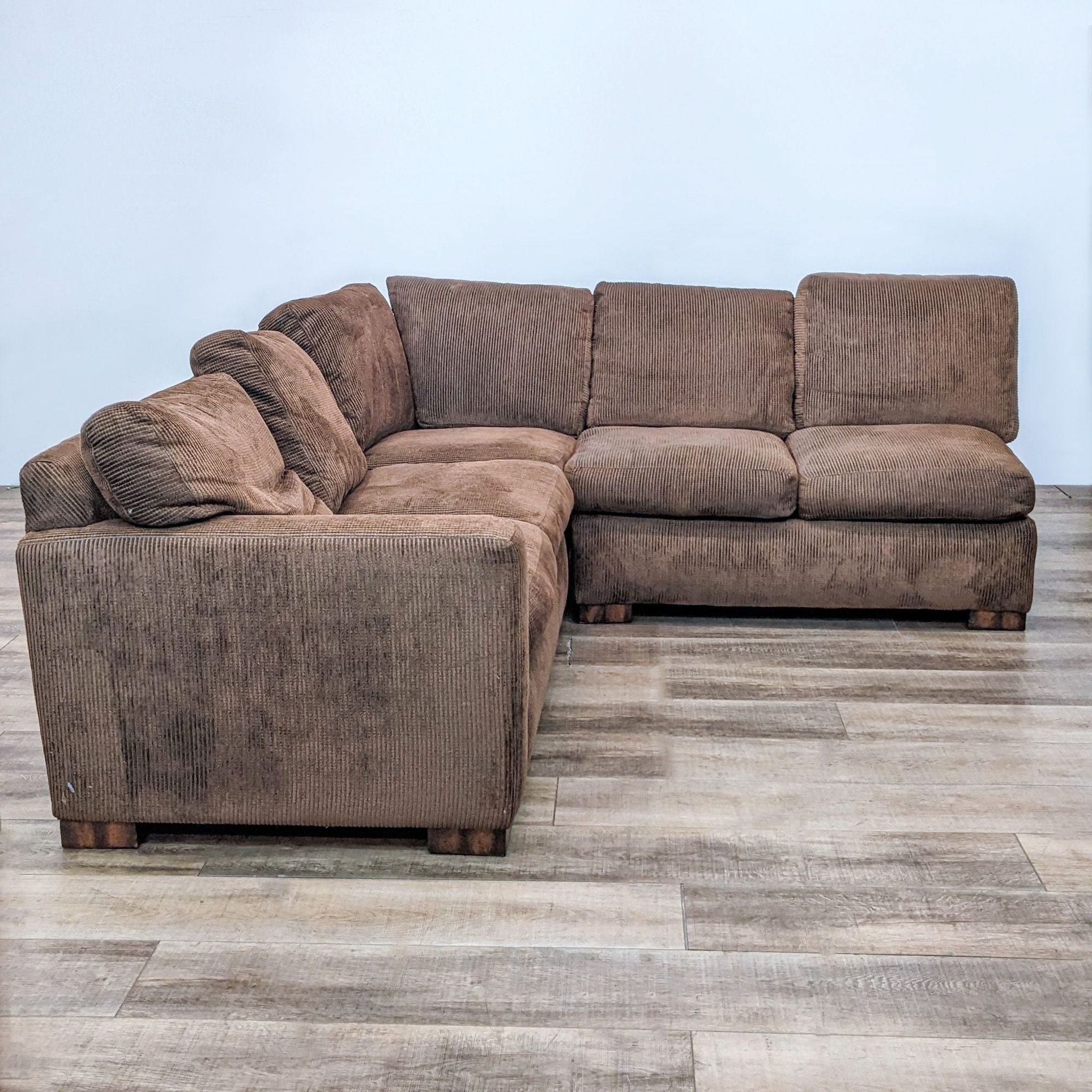 Flexsteel brown two-piece sectional with plush cushions and wooden block feet, shown in a well-lit room with wooden flooring.
