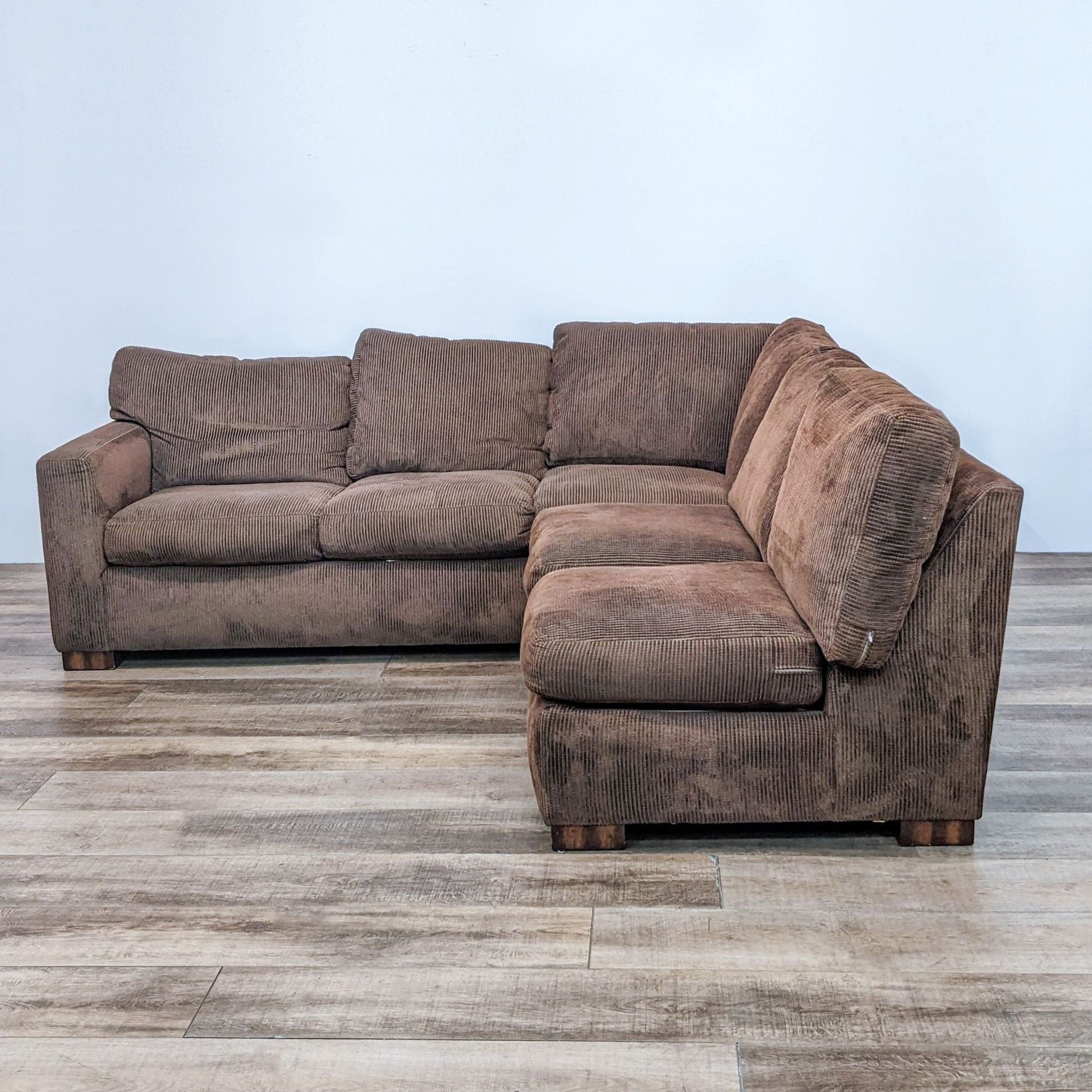 Contemporary Flexsteel brown sectional sofa with down wrapped cushions and a wood finish, displayed on laminate flooring.