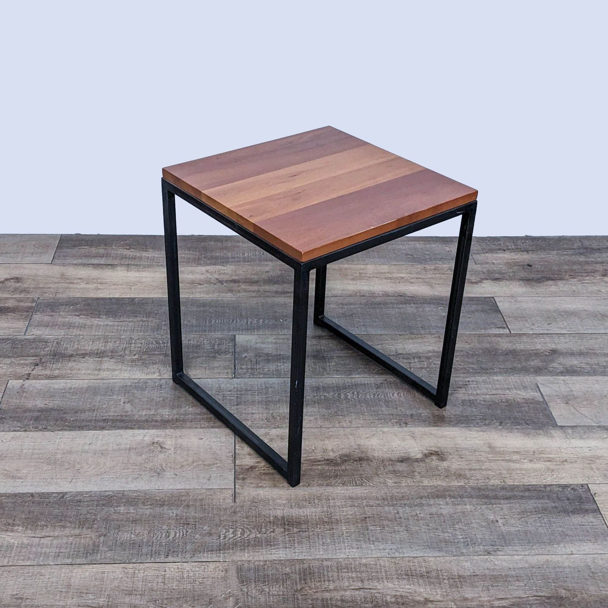 Reperch brand end table with a wooden top and a sturdy metal base, on a wood-patterned floor.