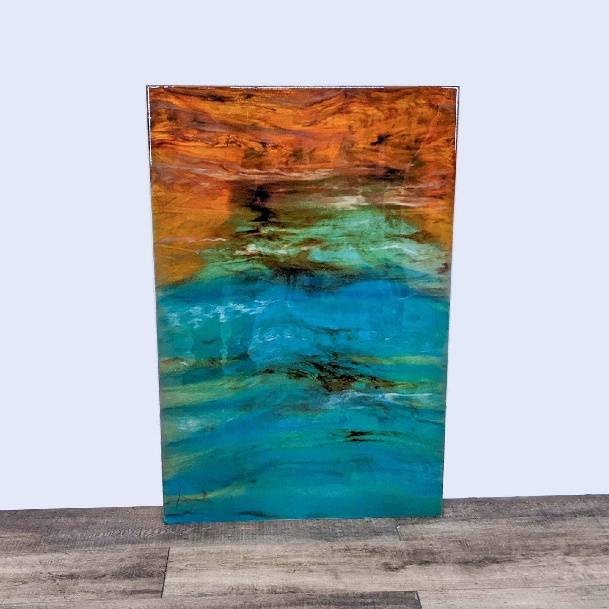 Abstract art print with vibrant gradient from teal to amber, displayed on a wooden floor against a plain background.