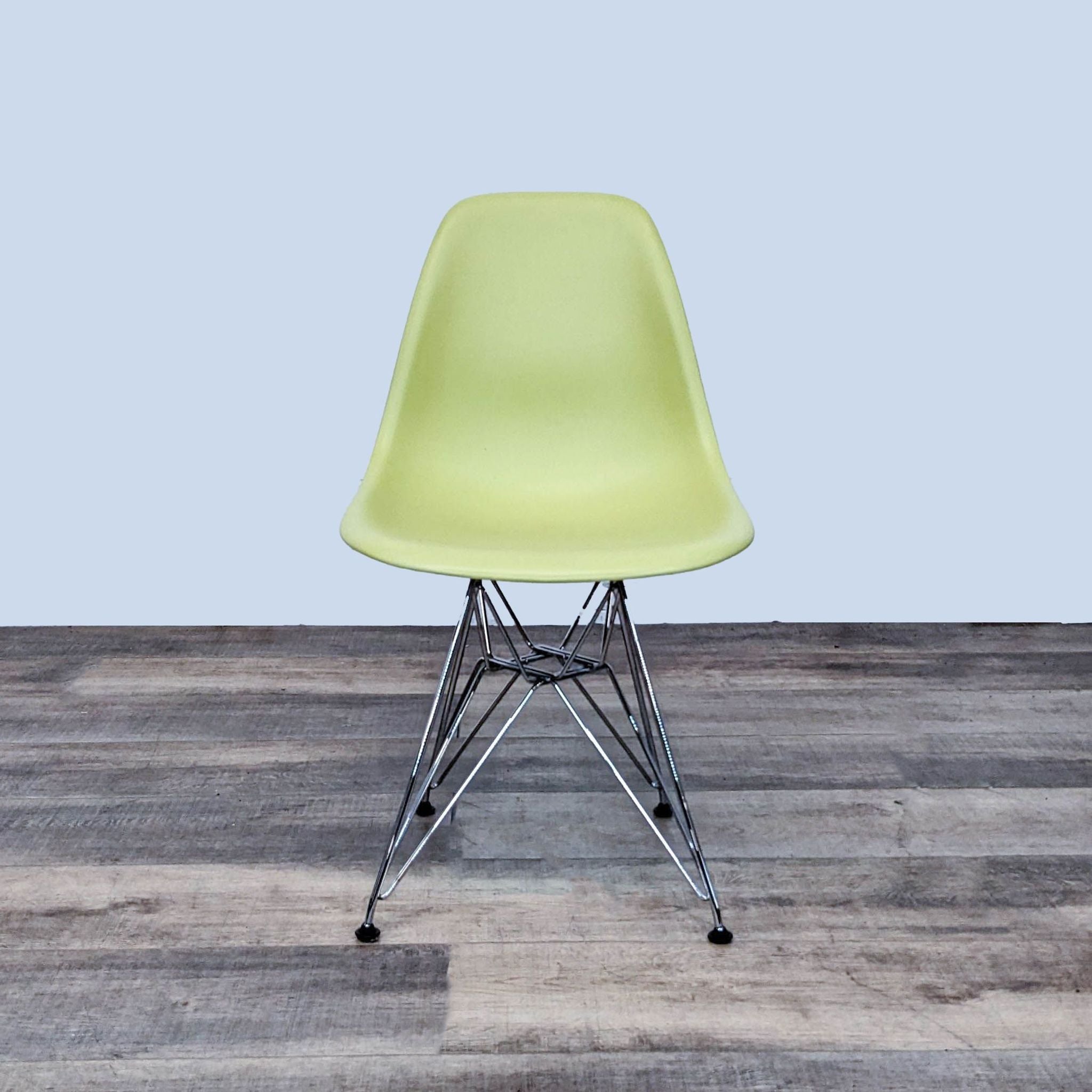 Alt text 1: A light green Vitra Eames dining chair with a molded plastic seat, chrome Eiffel-style base, on a wooden floor.