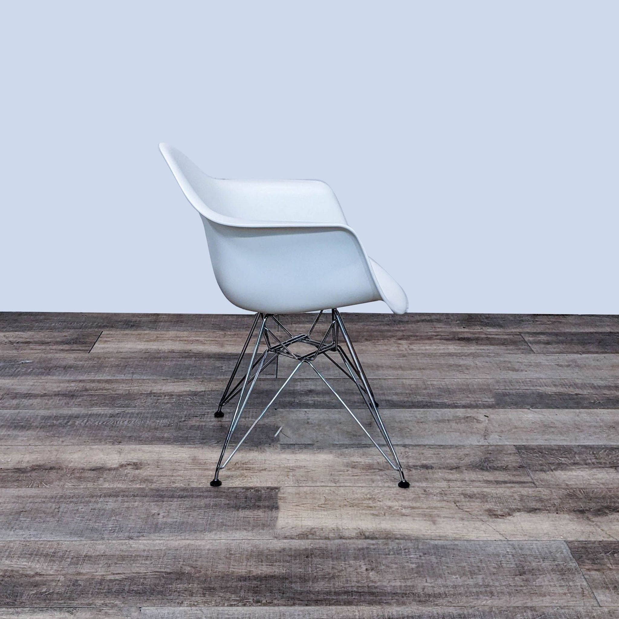 Eames molded plastic armchair by Herman Miller with a chrome wire base, shown in profile view on wooden flooring.