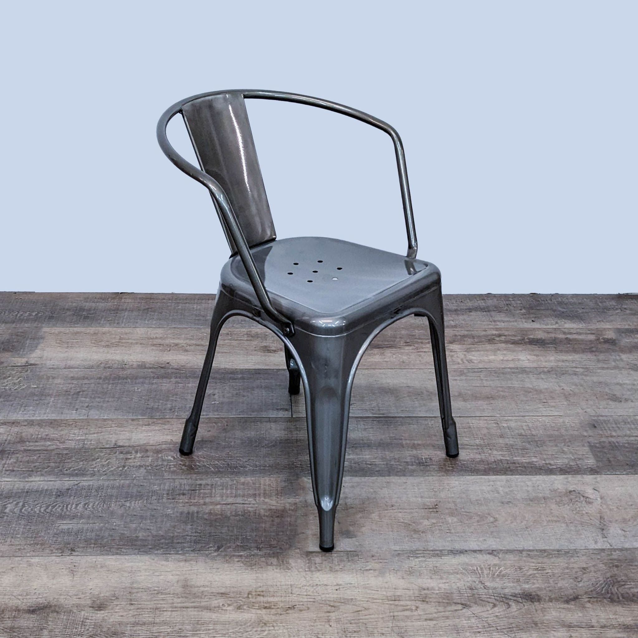 Reperch industrial metal dining chair with a curved single slat back, ergonomic design, and stackable structure on a wooden floor.