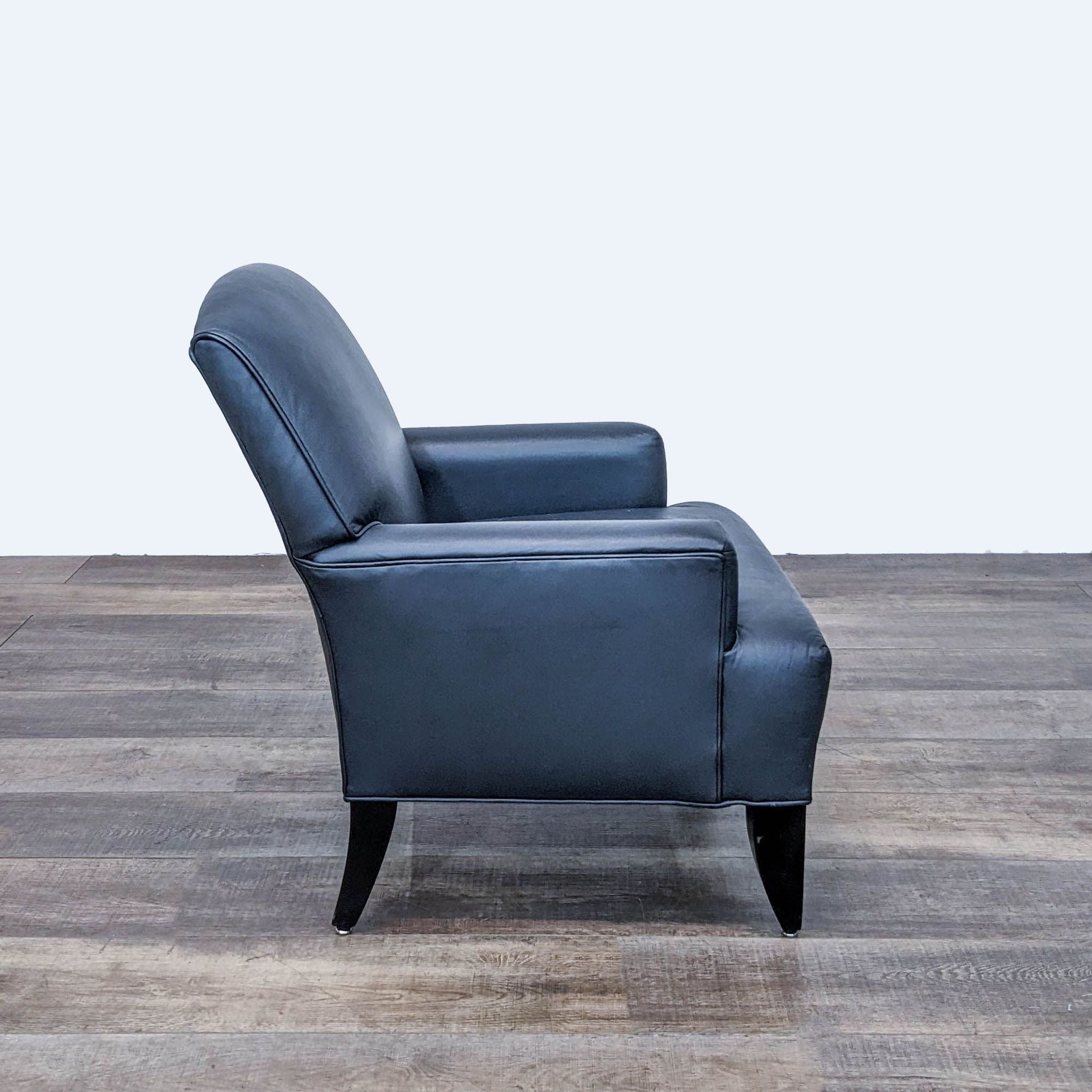 Side angle view of Reperch navy leather lounge chair with curved backrest and dark wooden legs.