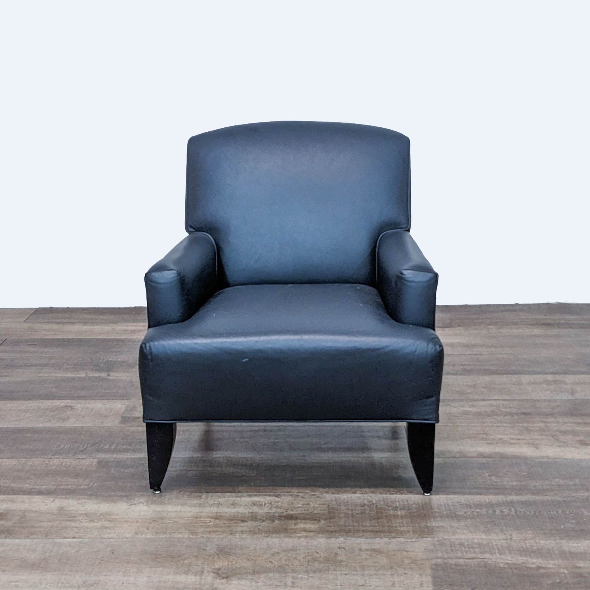 Reperch navy blue leather club chair with arched back and tapered wooden feet, front view on wood floor.