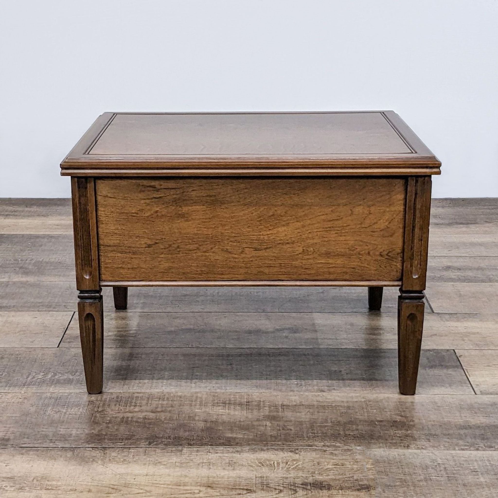 Reperch wooden end table with warm finish, classic design, detailed carvings, and two drawers with metal handles.