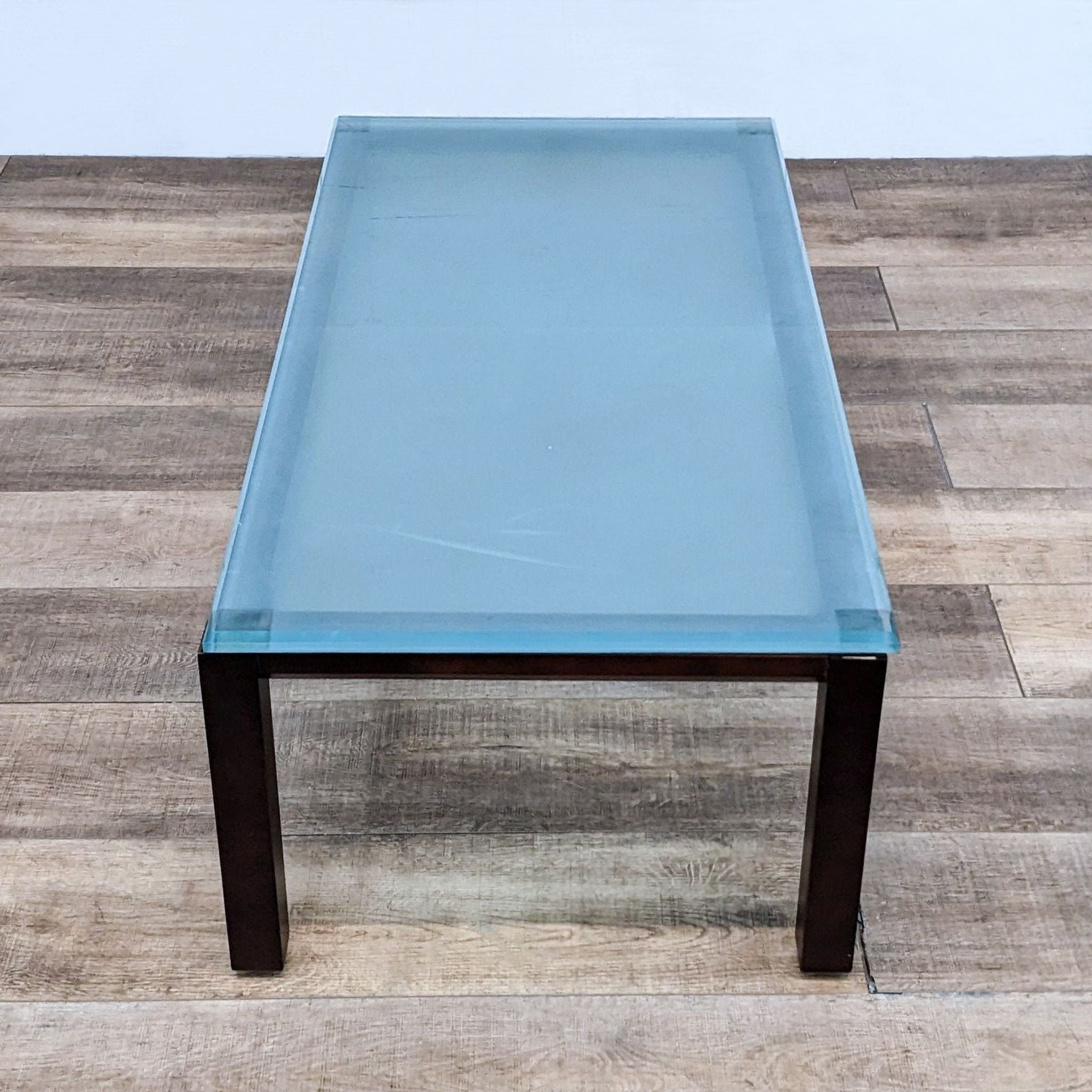 Opaque glass-topped coffee table by Reperch, with a solid wood frame, seen from an overhead angle.
