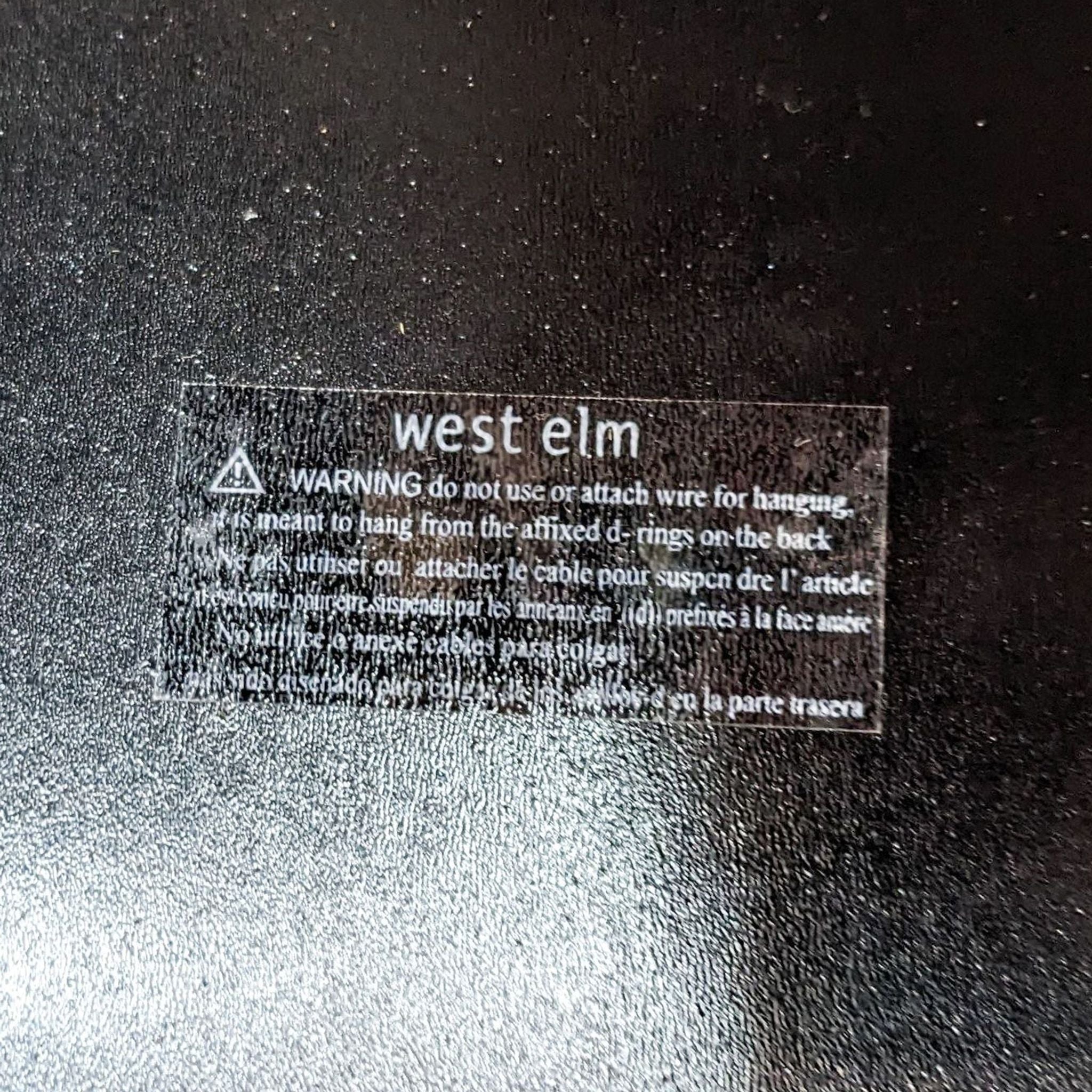 Warning label on a West Elm mirror advising against using wire for hanging.