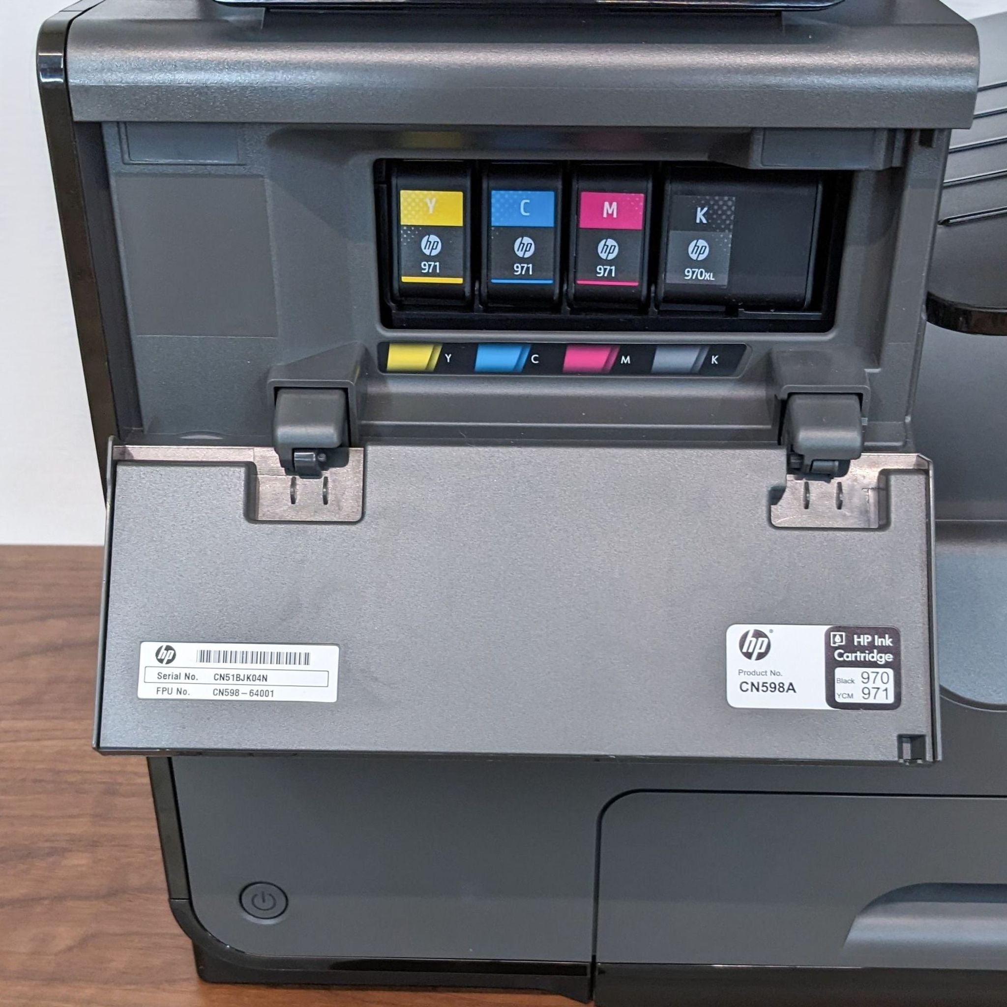 Close-up of HP OfficeJet Pro's ink cartridge compartment with CMYK cartridges installed and model details visible.