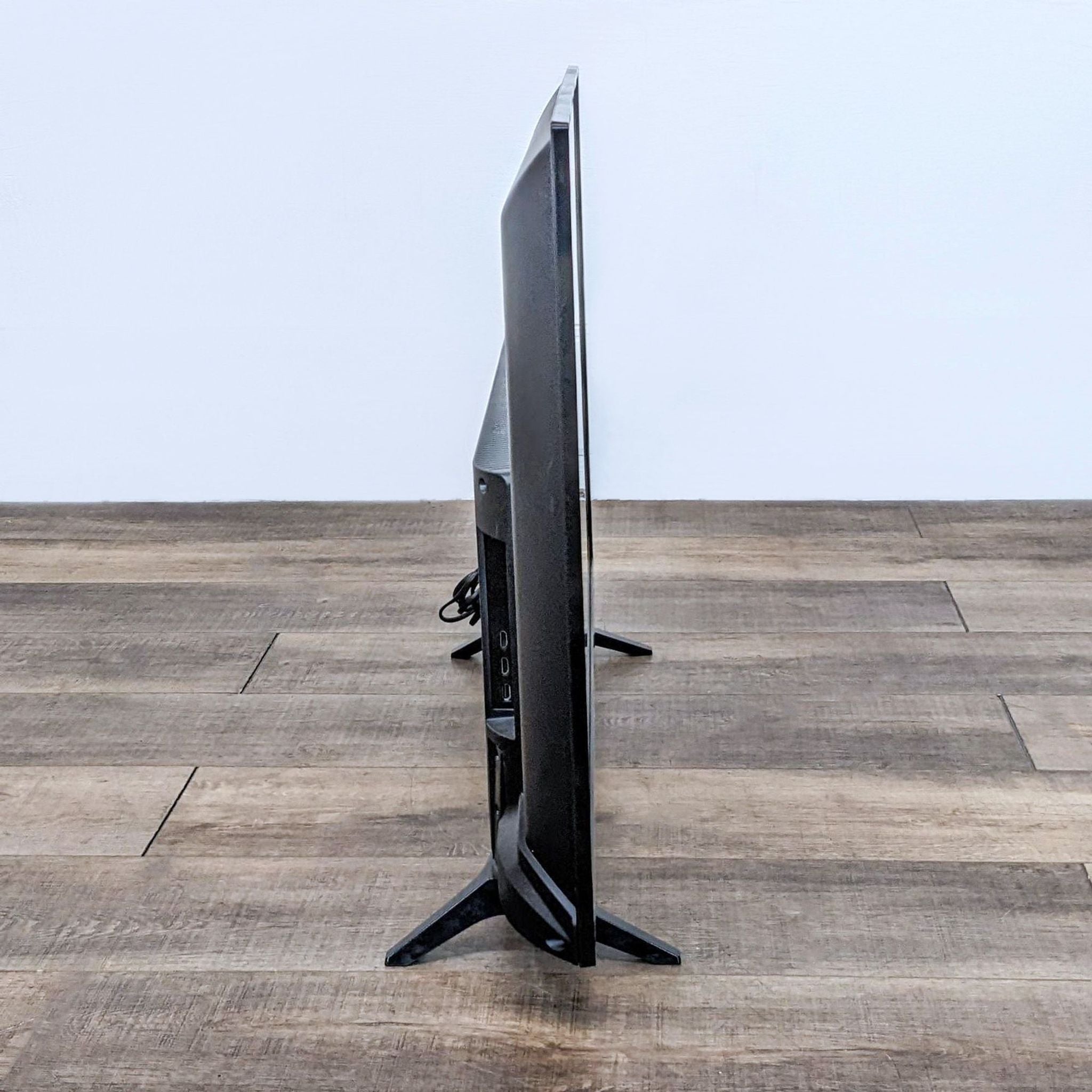 Side angle of an LG TV showcasing its slim profile and stand on a wooden surface.