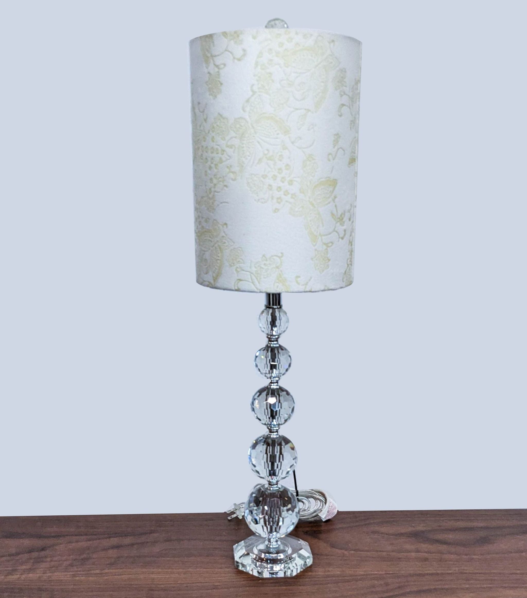 Reperch brand elegant table lamp with a patterned white shade and a stacked crystal base on a wooden surface.