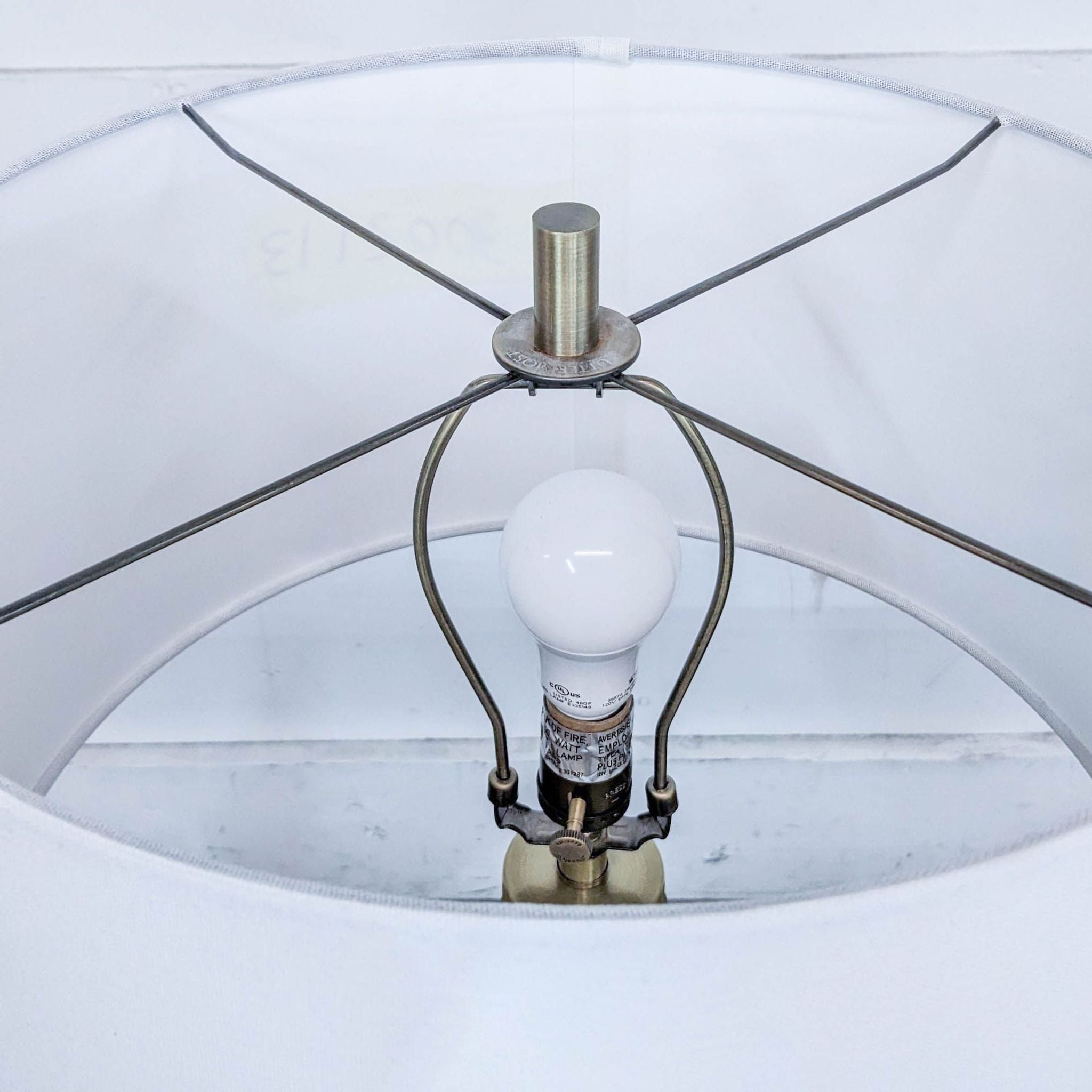 Top view of a Reperch lamp showing white shade, bulb, and brass accents on a light background.