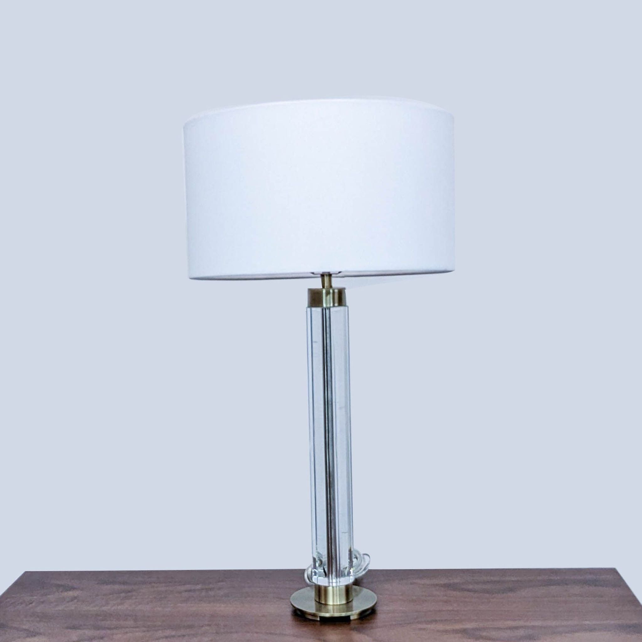 Reperch brand table lamp with clear cylindrical body and white shade on wooden surface.