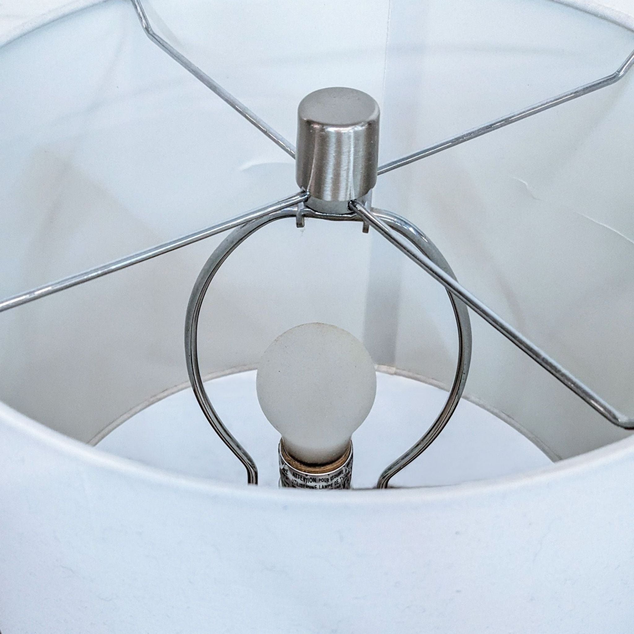 Interior view of a lampshade showing the bulb socket and metal frame on a Reperch lighting item.