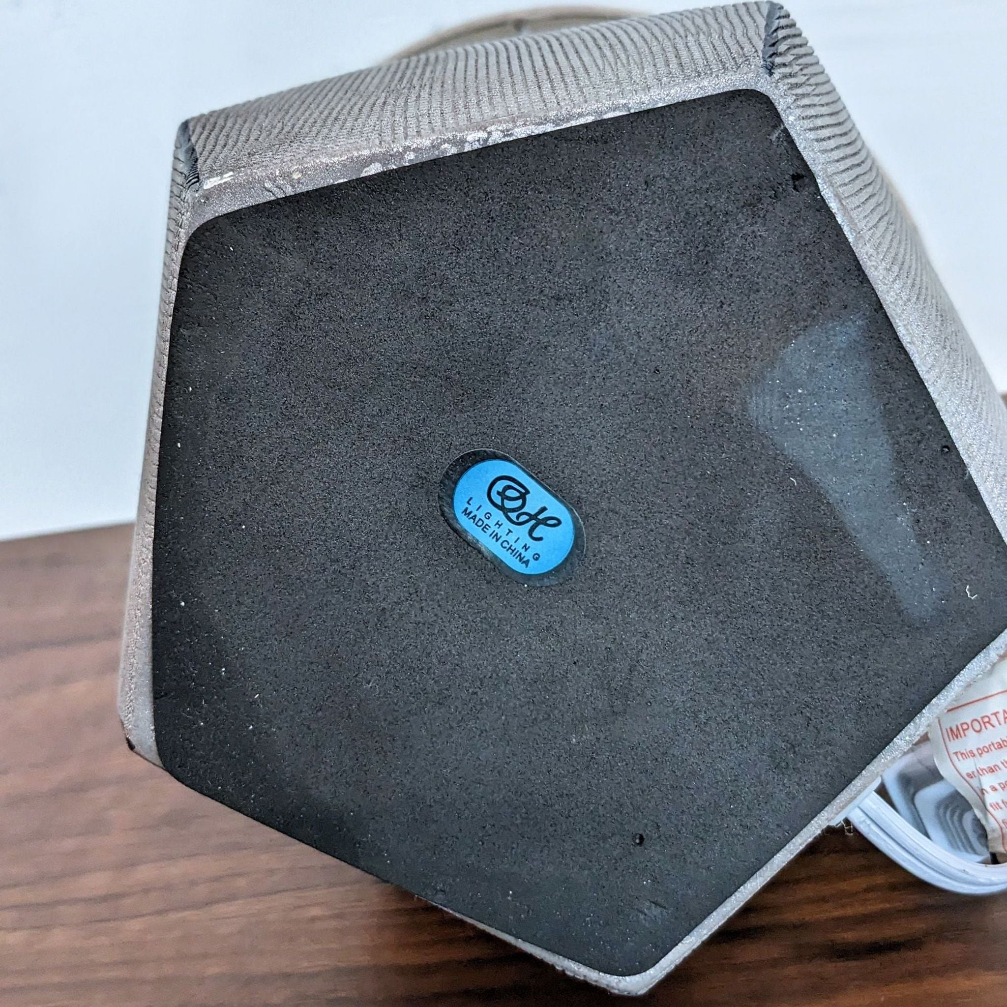 Underside view of a Reperch lamp showing brand sticker and felt padding on its geometric base.