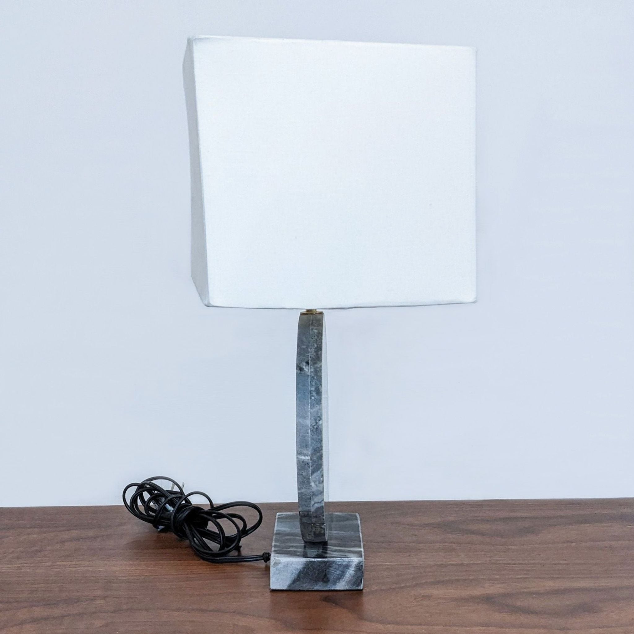 Reperch brand table lamp with a square white shade and marbled base on a wooden surface with coiled black cord.