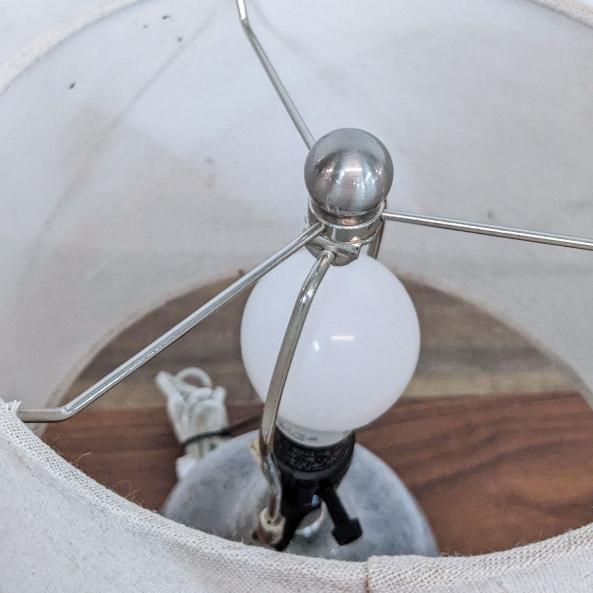 Reperch brand lamp with a white bulb and silver metallic fixture inside a fabric lampshade.