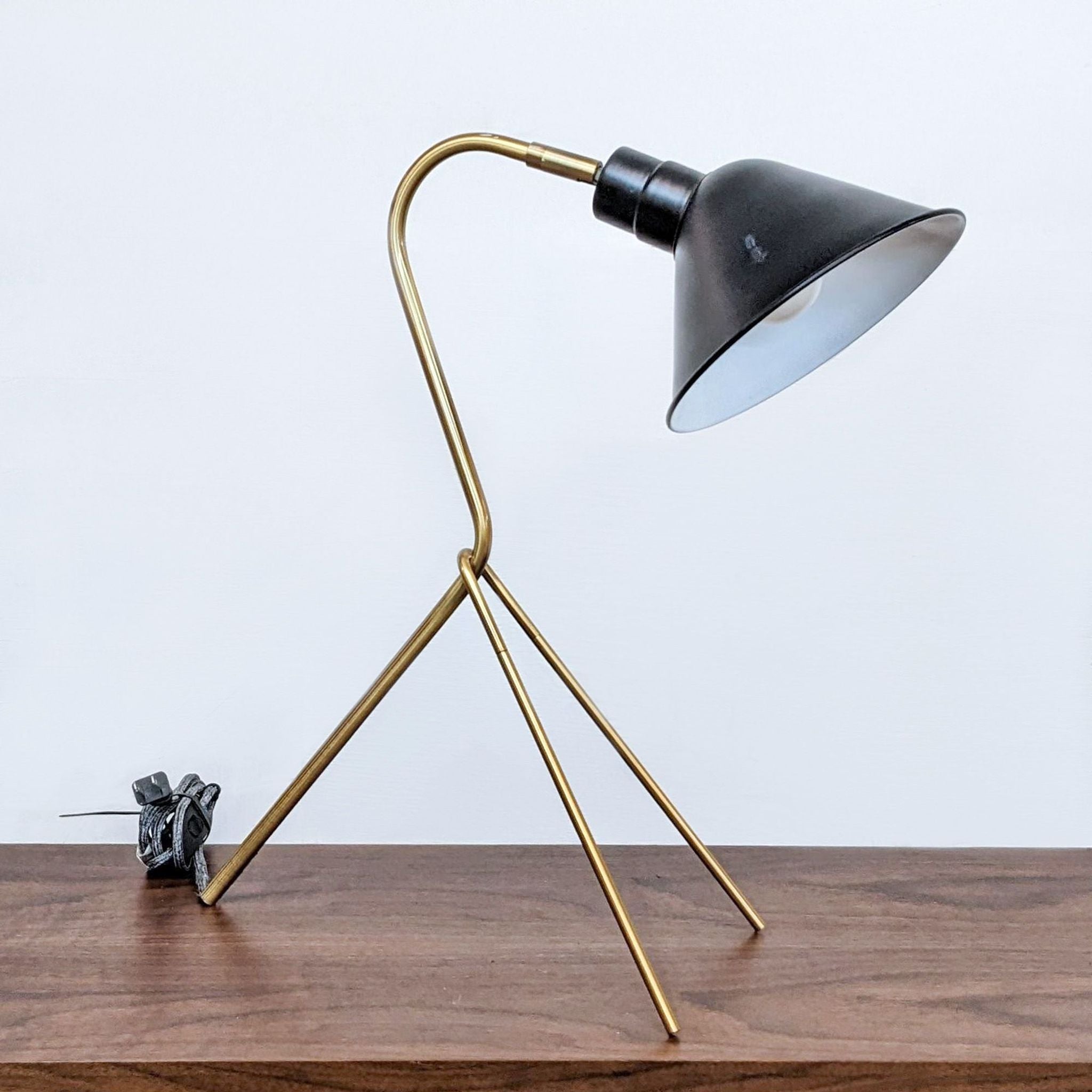 Modern Reperch lighting, featuring a metallic desk lamp with a distinctive tripod base and angled black shade.