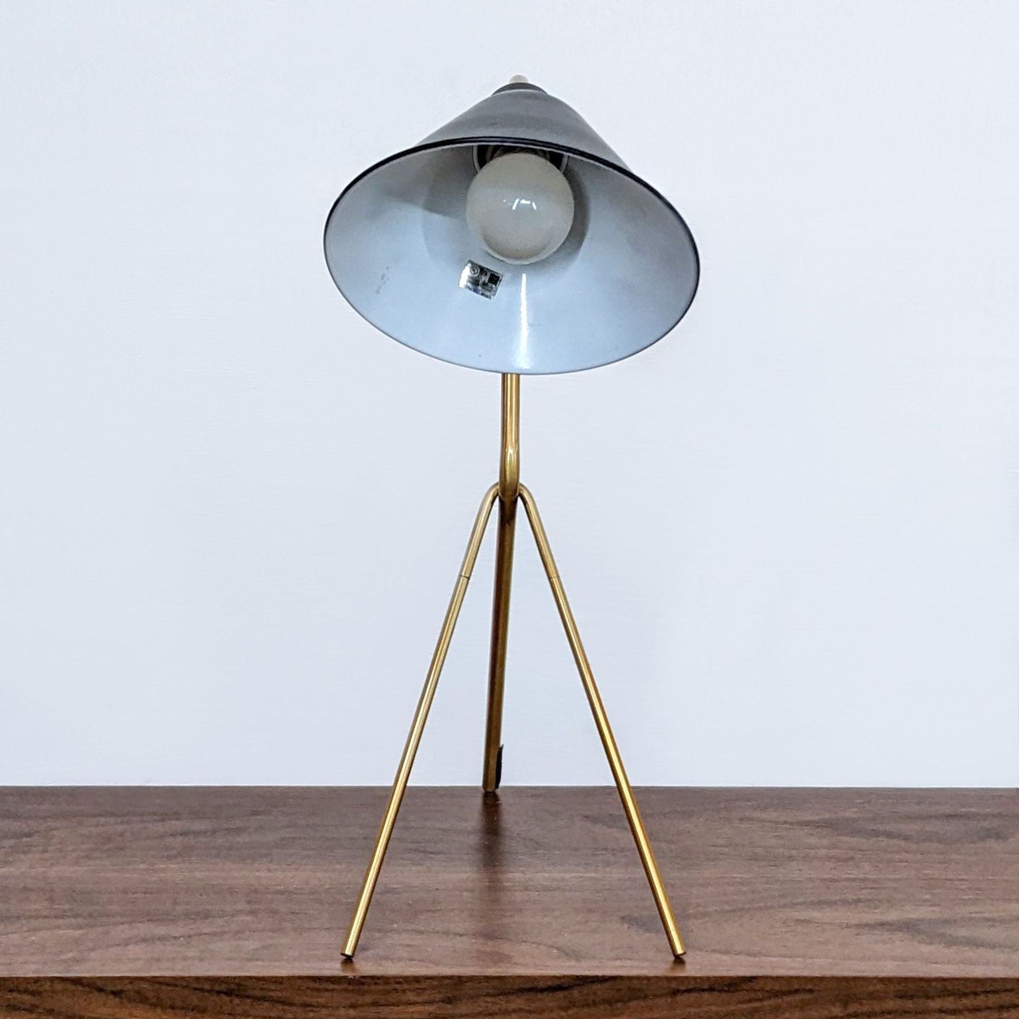 Reperch brand tripod table lamp with a metallic finish and a conical shade on a wooden surface.