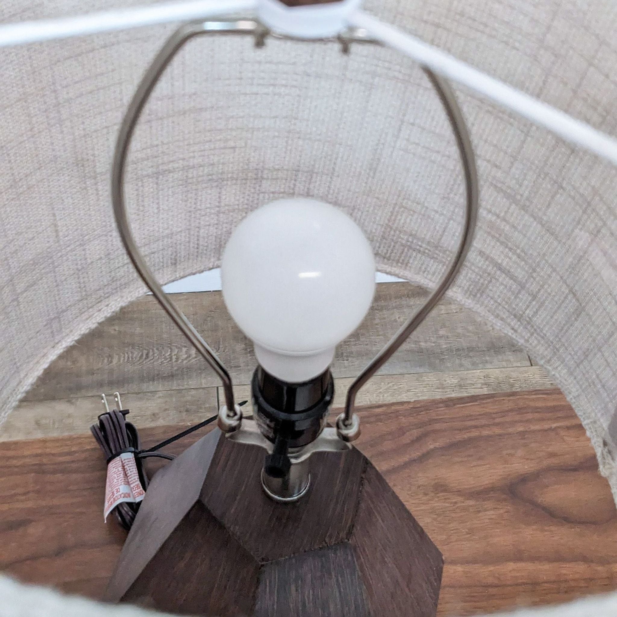 Interior view of a Reperch table lamp, showcasing the bulb and inner shade structure above a wooden base.