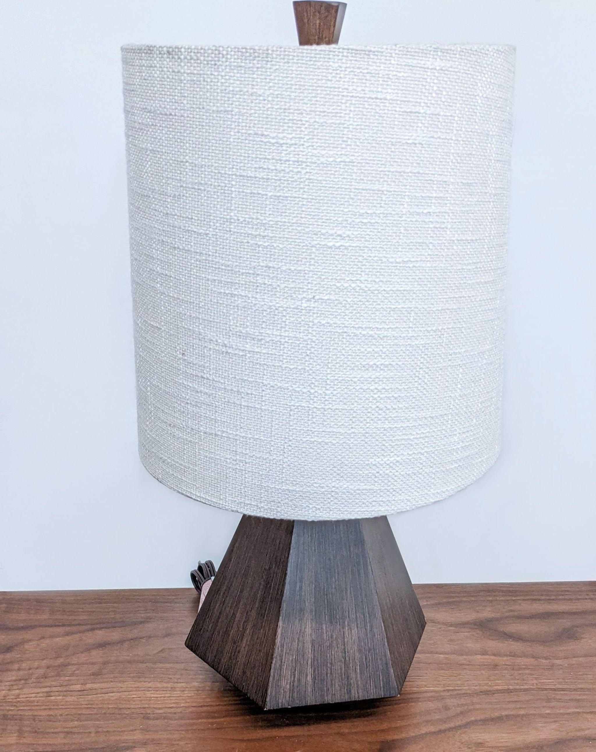 Reperch brand table lamp with white fabric shade and angular wooden base on a wooden table.