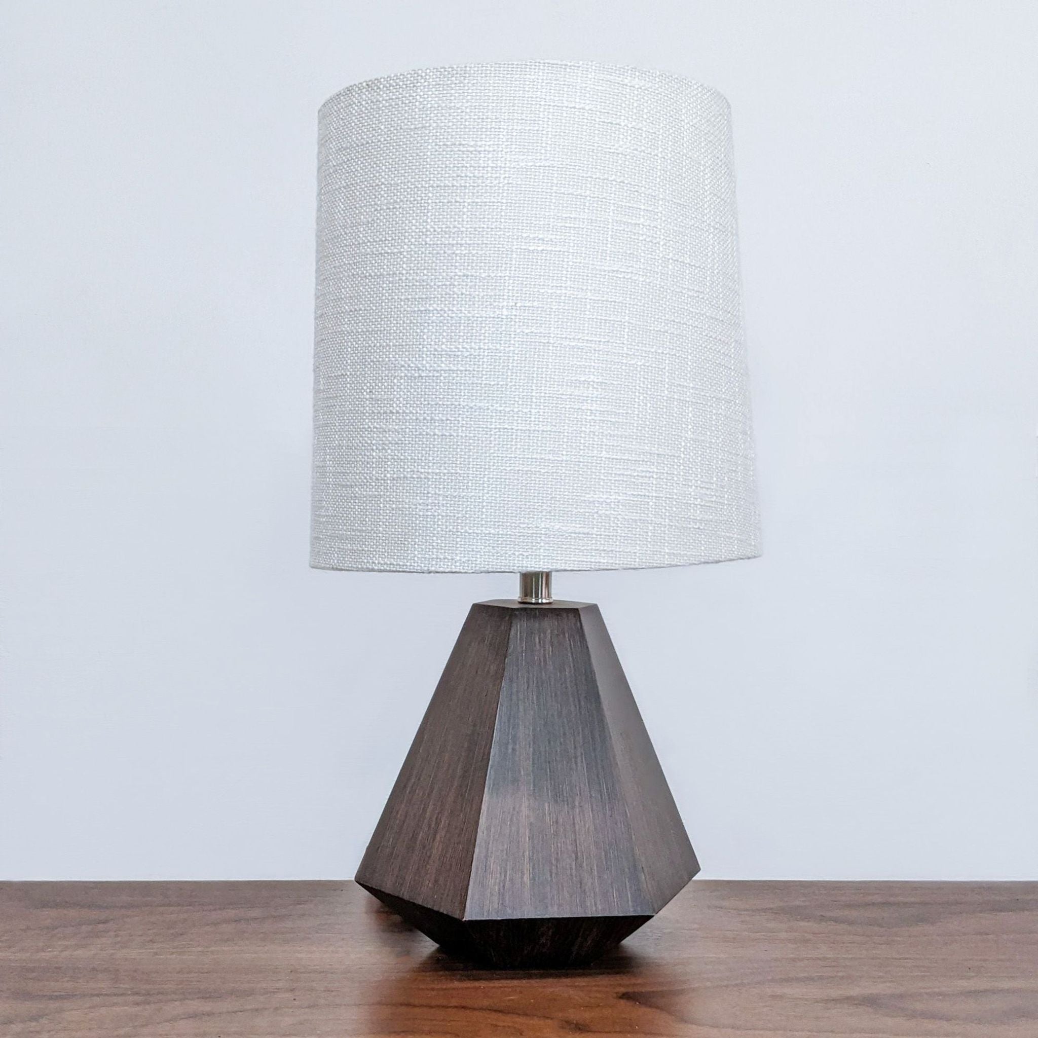 Reperch brand table lamp with a textured white shade and a geometric wooden base on a table.