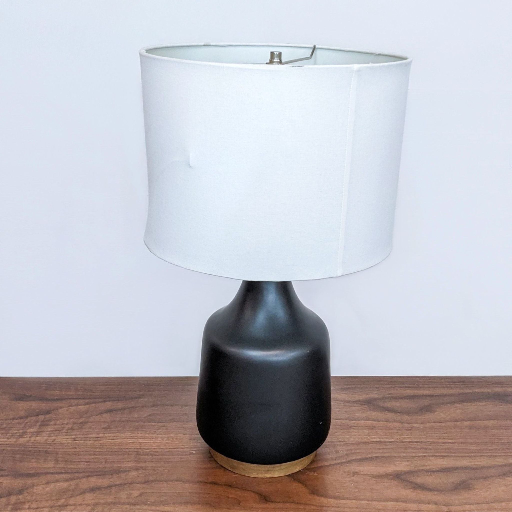 West Elm table lamp with a white shade and black base on a wooden surface.