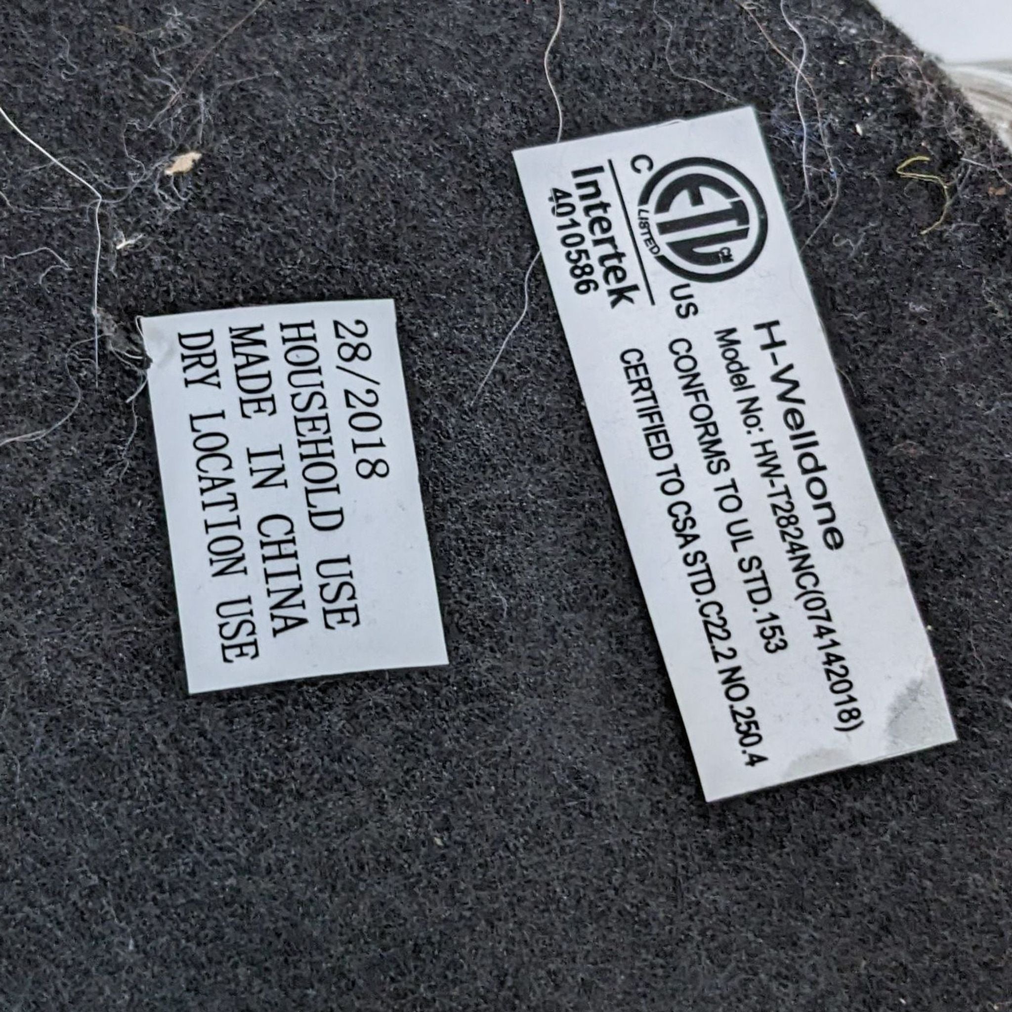 Two labels on a fabric surface with text indicating product certification and specifications for a Reperch lighting product, made for household use and dry locations.