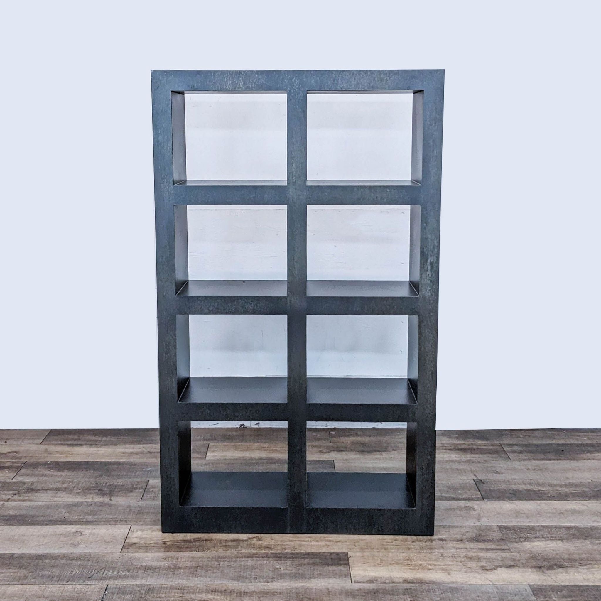 Crate and Barrel steel bookshelf with graphite lacquer finish, shown in frontal view on a wooden floor.
