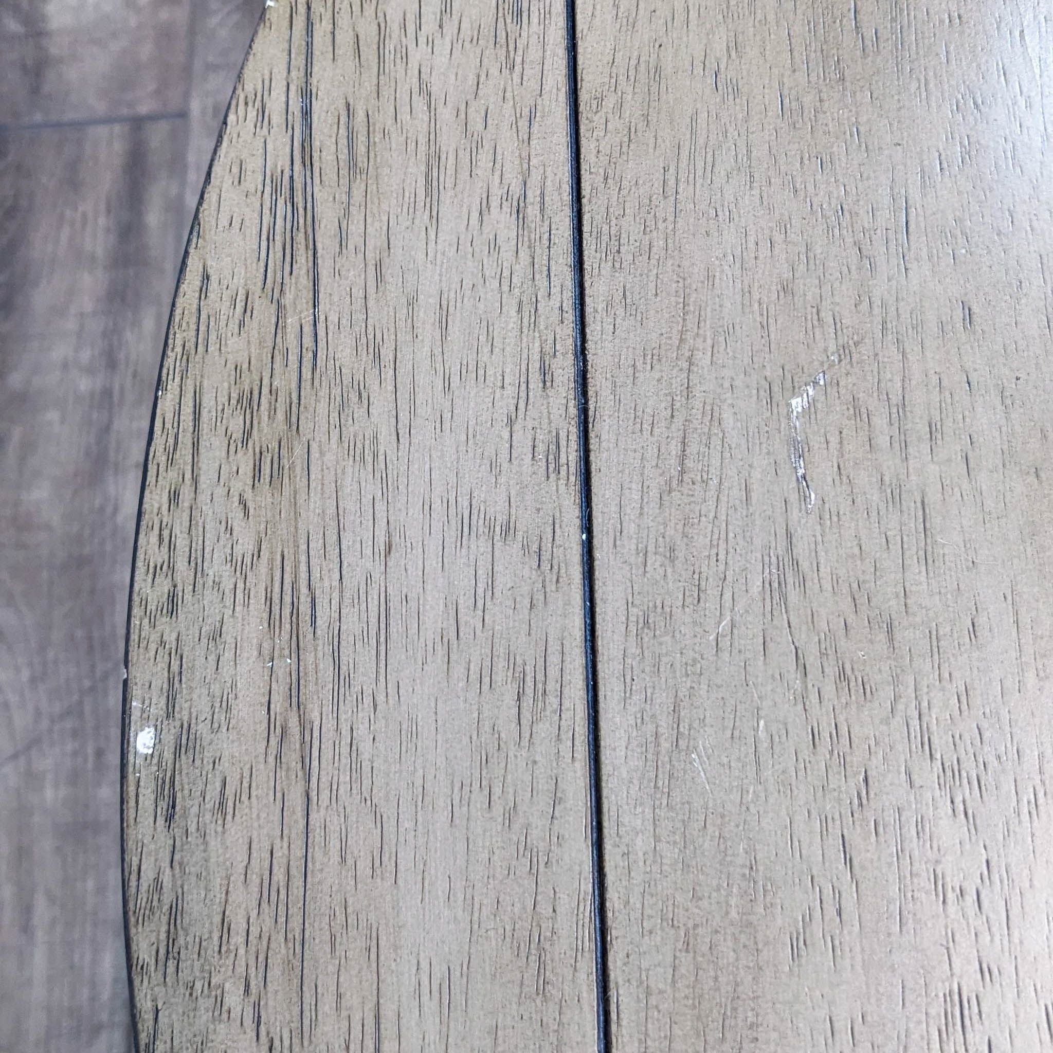 Close-up texture detail of Reperch coffee table showing wood grain on planked surface. Simple, subdued lighting.