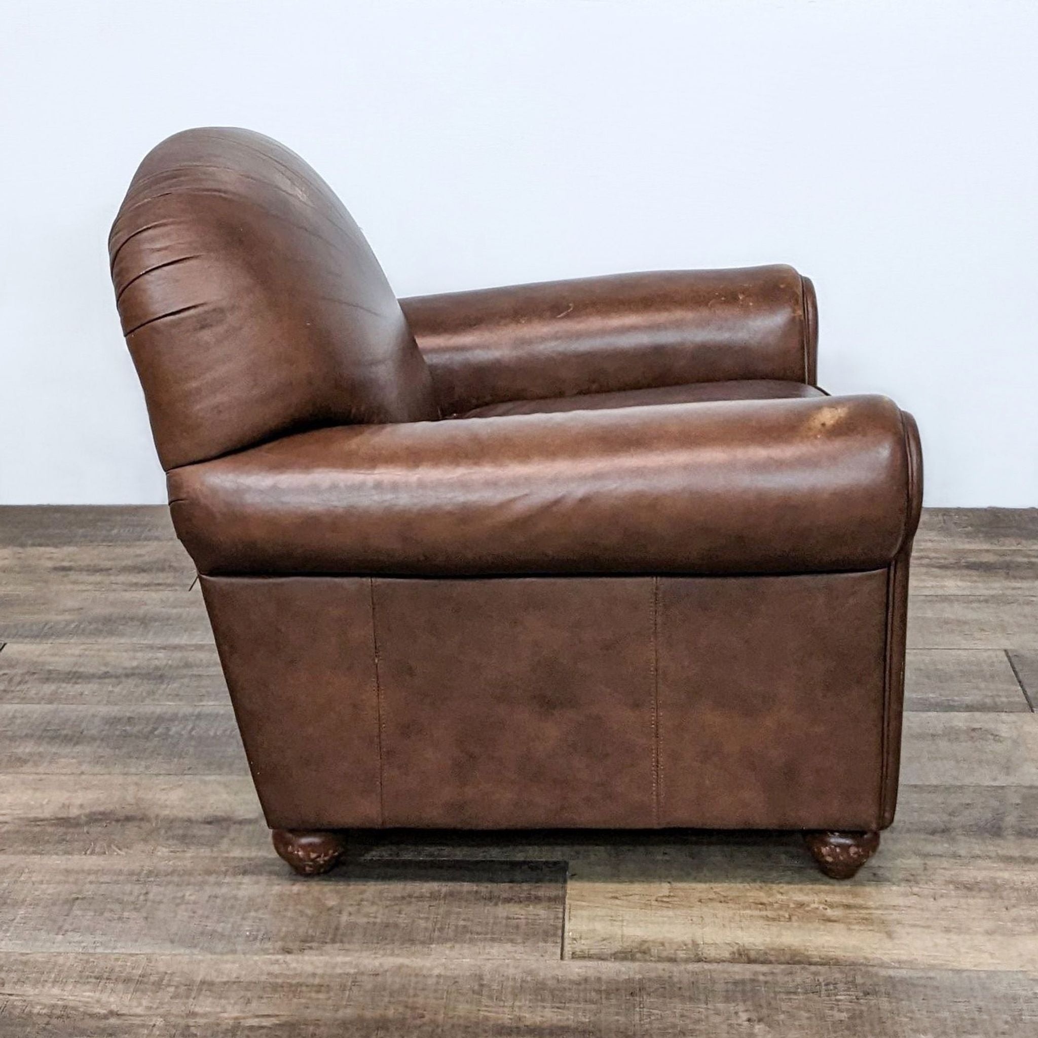 Brown Reperch contemporary club chair showcasing its profile with rolled arms and sturdy wooden feet.