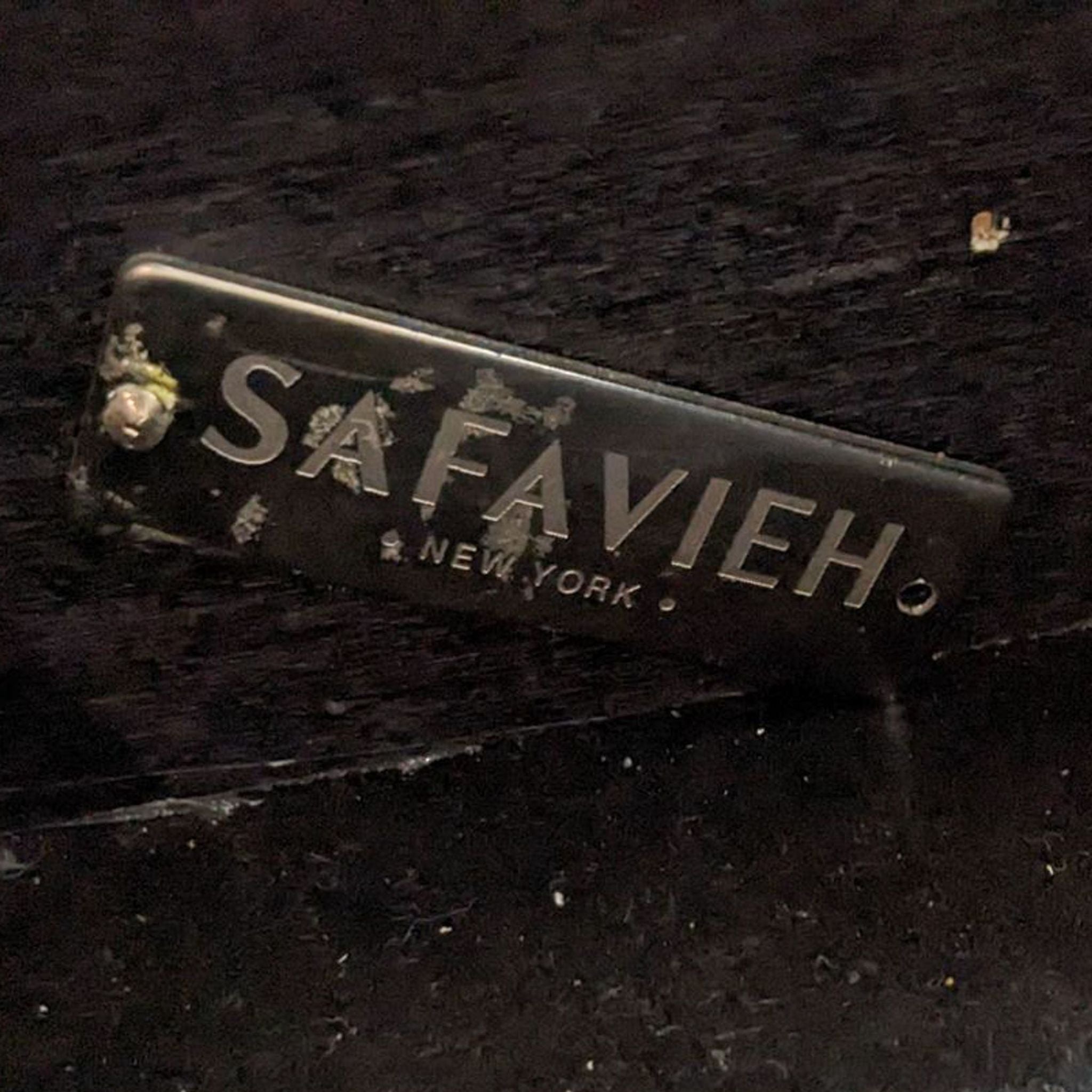 Close-up of a Safavieh brand label on a black nightstand showing scratches and wear.