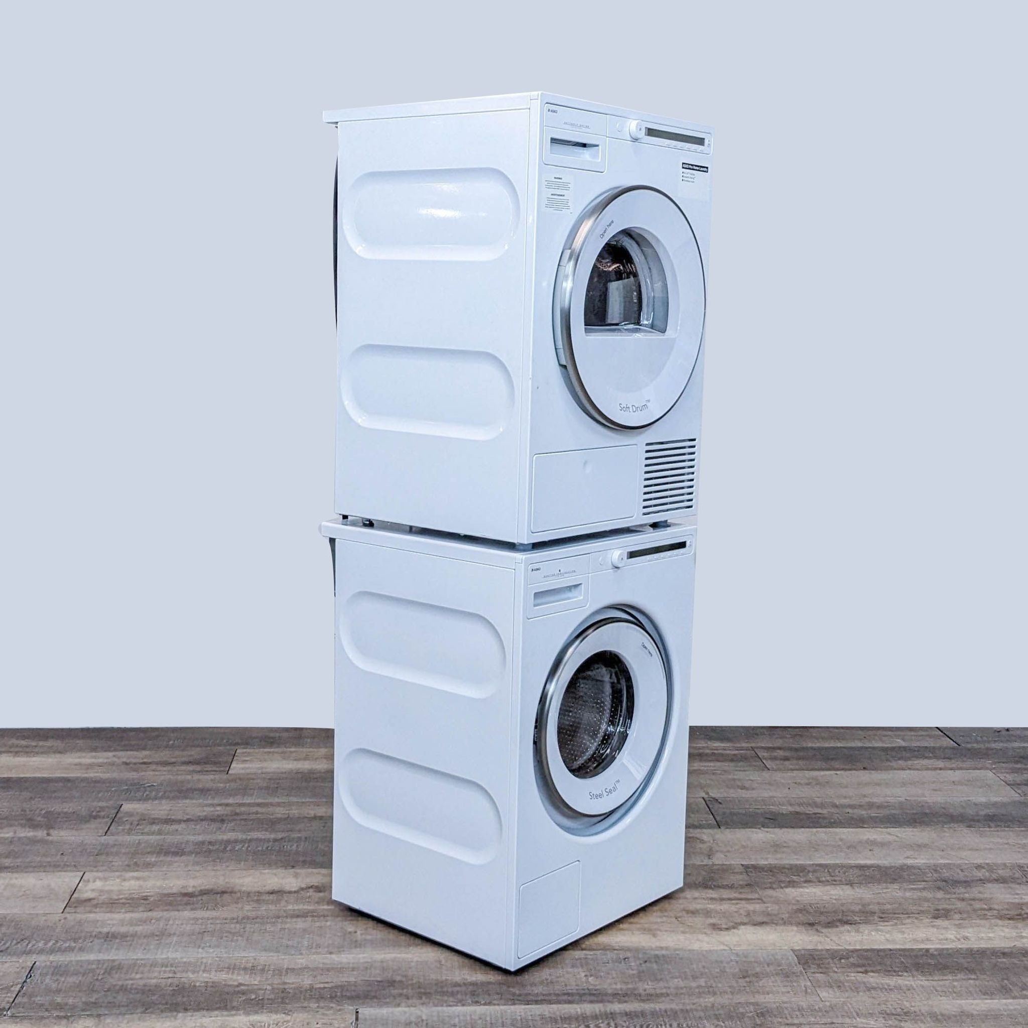 Rear view of an ASKO stackable washer and dryer set showcasing the electrical and venting connections with a grey background.