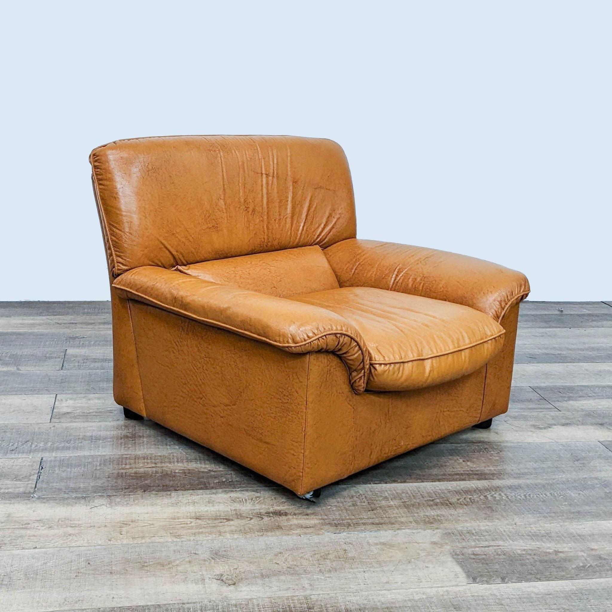 Reperch contemporary leather club chair with rounded arms and wooden feet on a wooden floor.