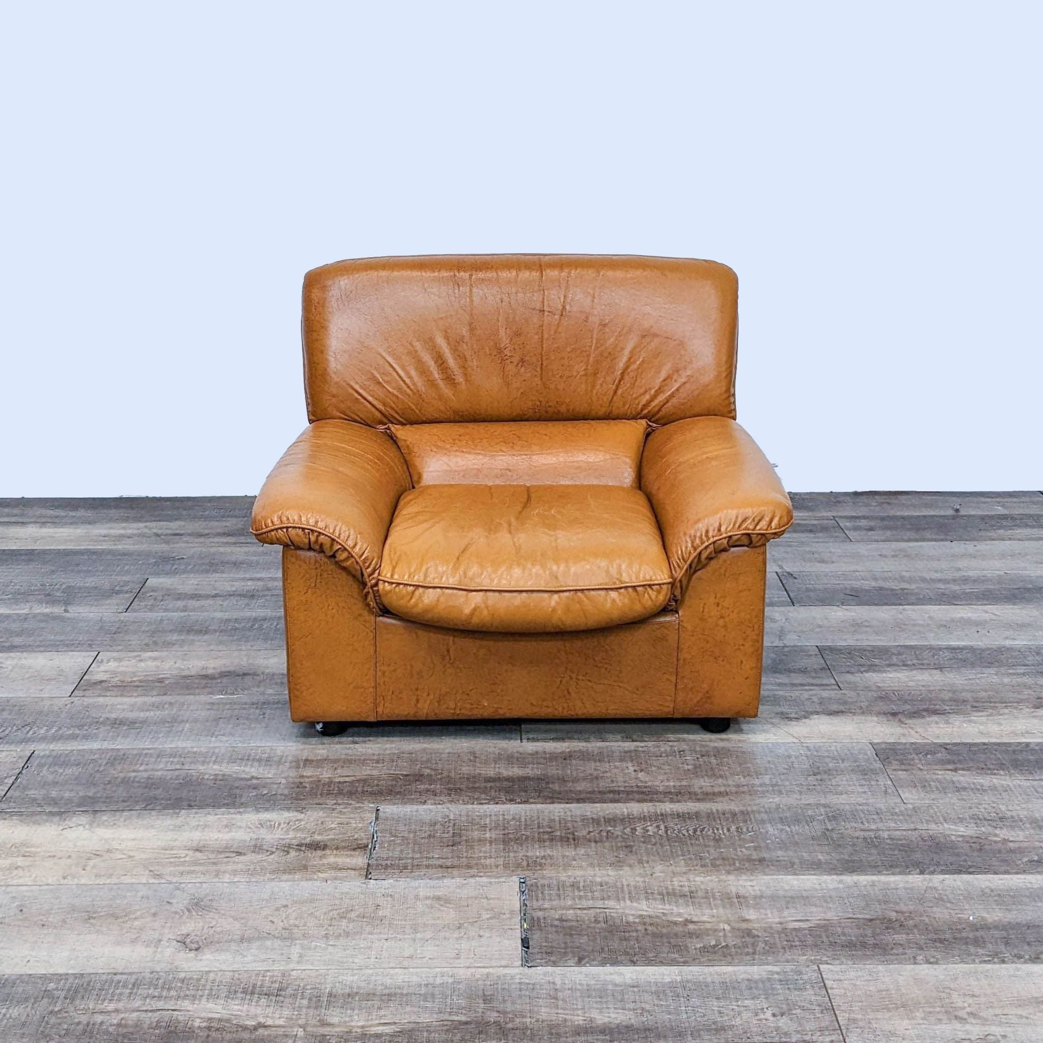 Reperch brand modern leather club chair with plush cushions, rounded arms, and wooden feet on a wood floor.