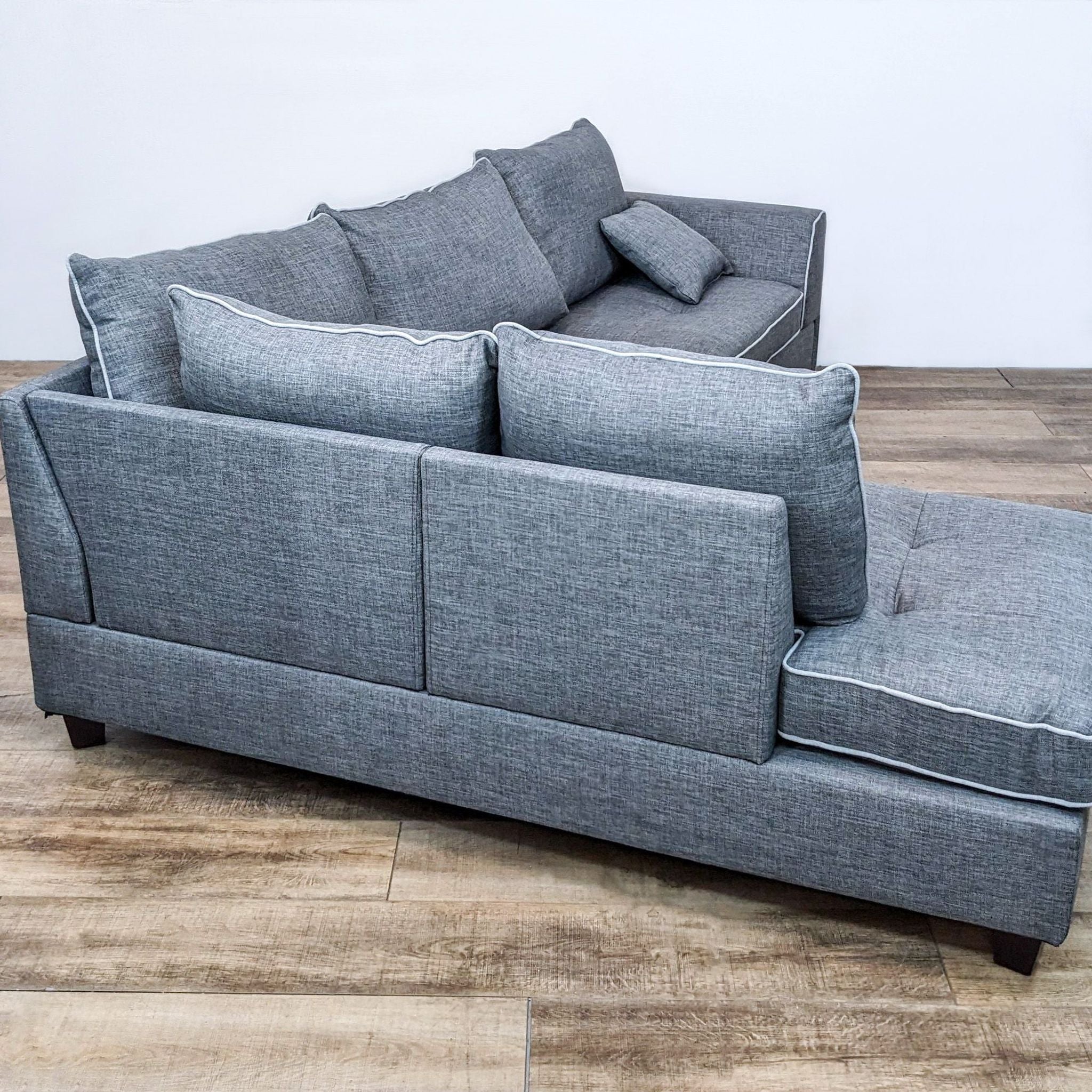 Side view of a Reperch gray fabric sectional with accent pillows and dark finished legs, showing the profile design.