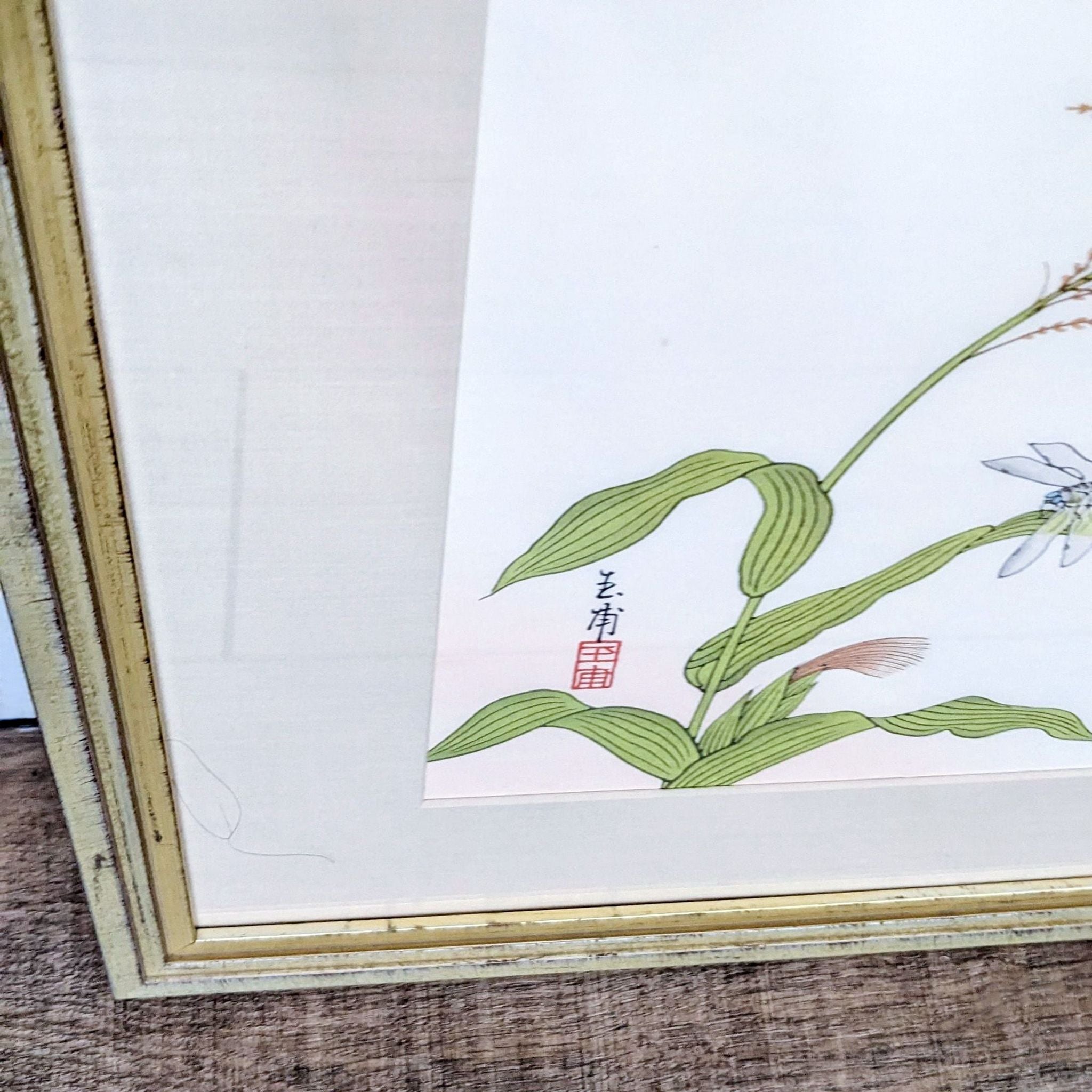 Botanical print with delicate leaves and dragonfly against Asian calligraphy, framed in gold by Reperch.