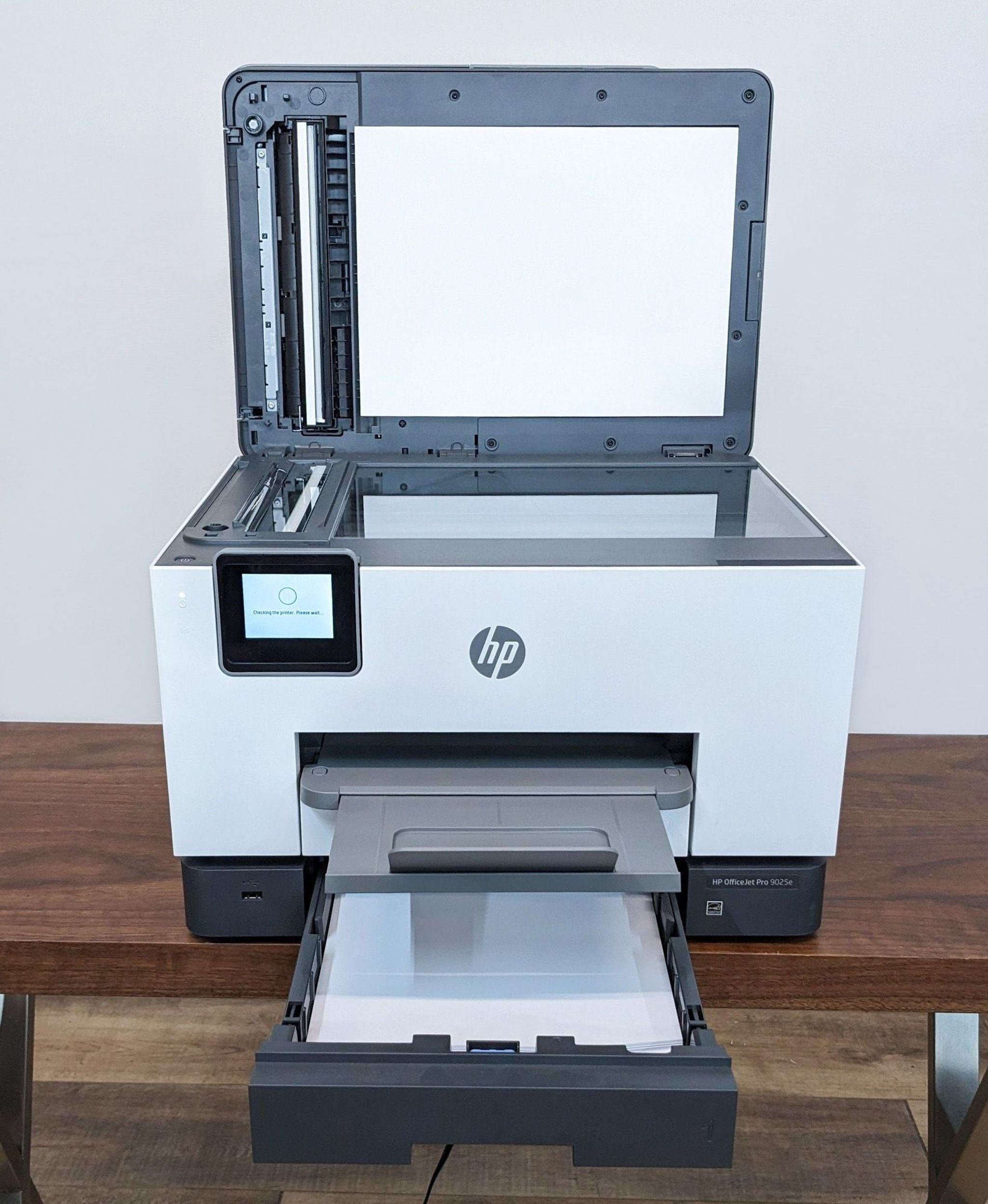 HP All-in-One printer open, showing scanning bed and paper tray, with touch screen interface for easy navigation.